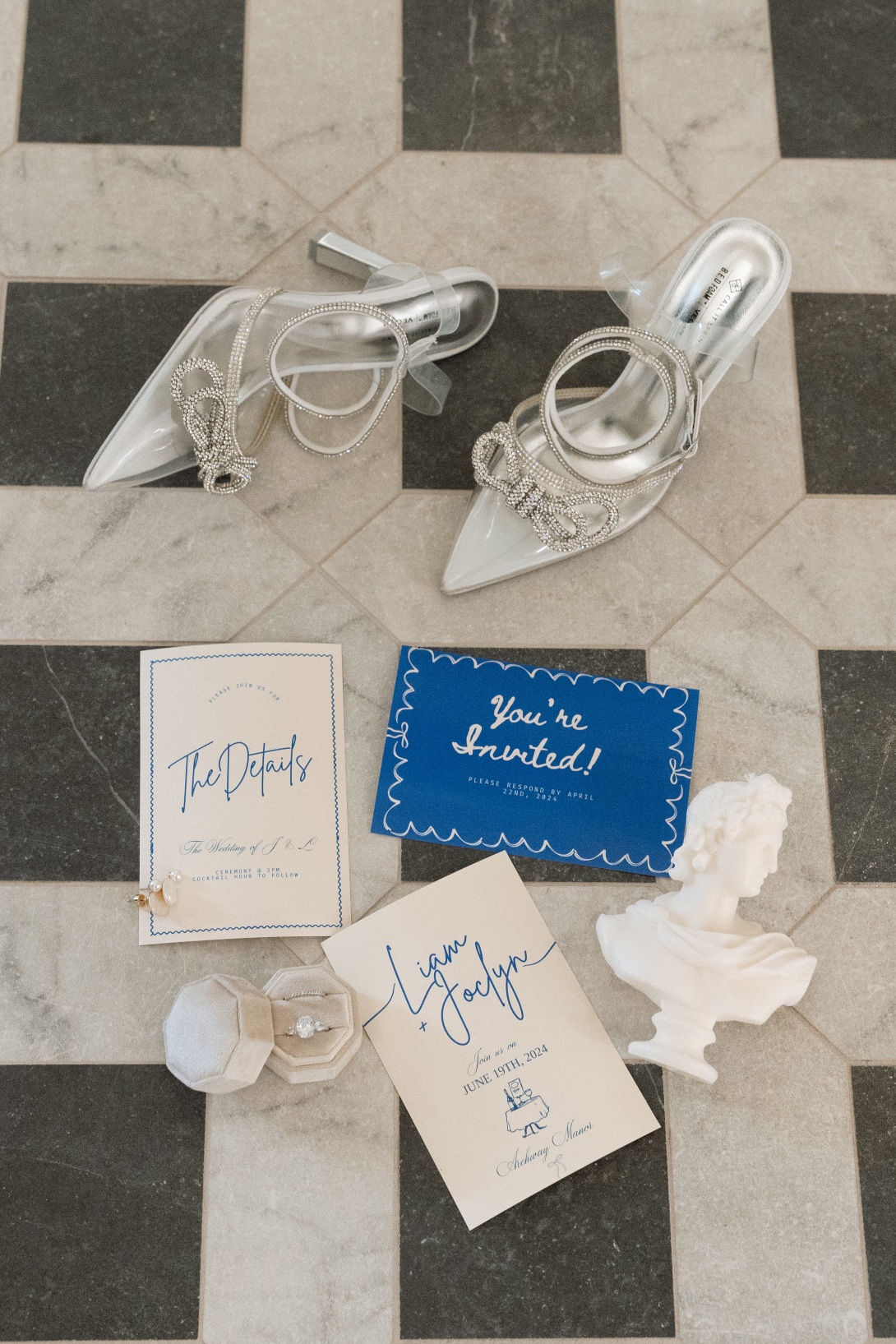 A flatlay image of the brides shoes, the invitations, and rings on the beautiful tiled floor of the foyer.