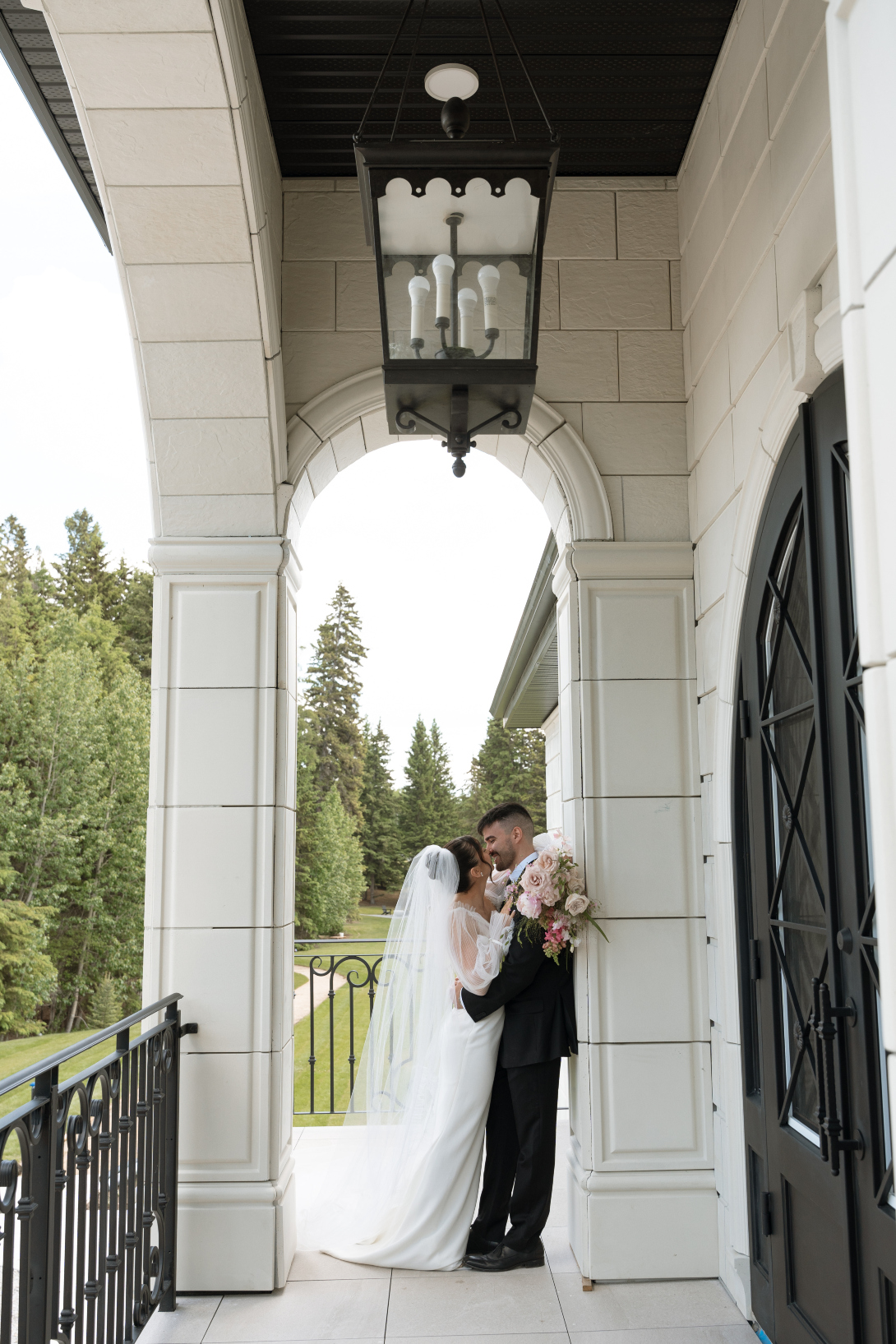 The couple out on the balcony, stealing a kiss under an arch.