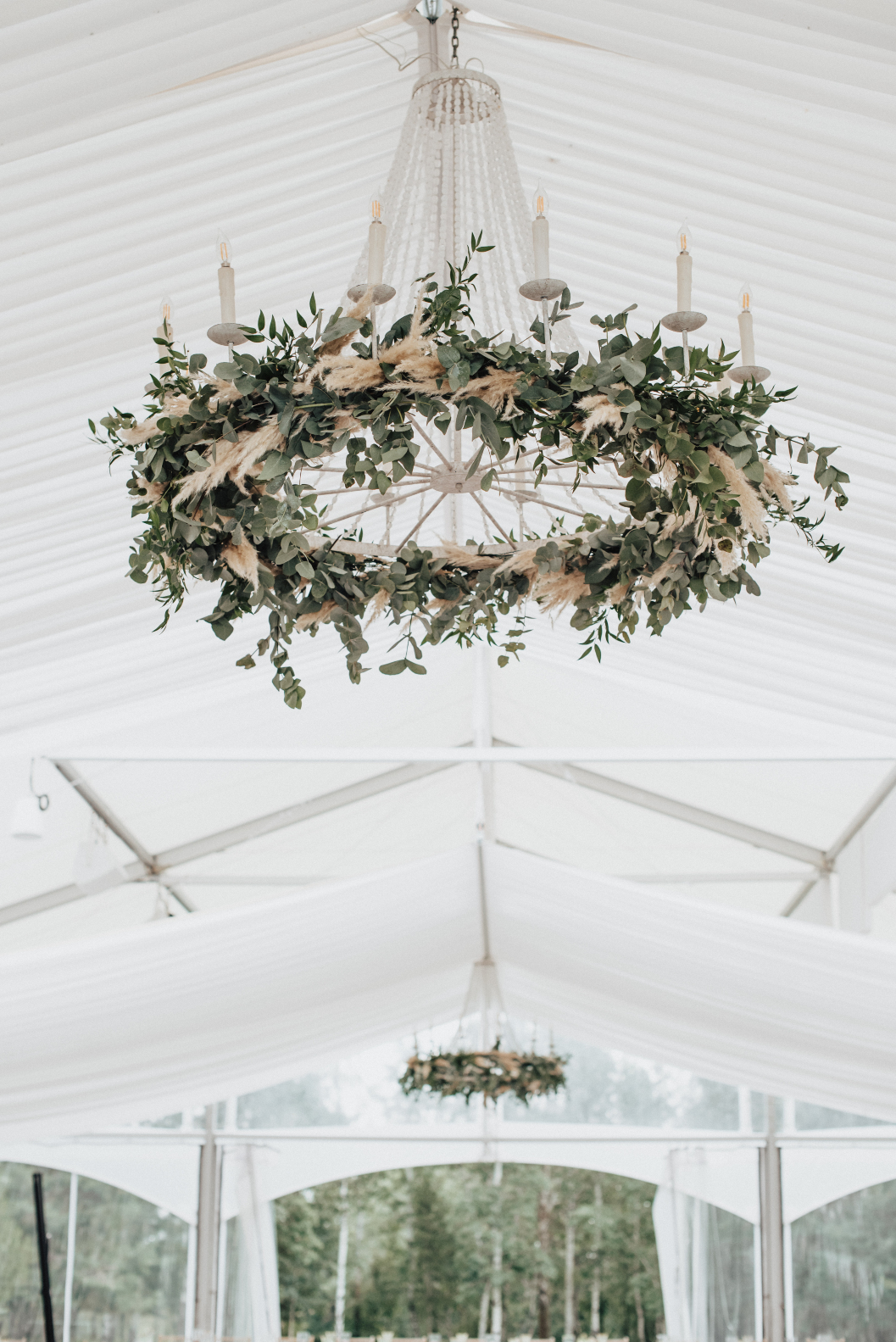 Chandeliers adorned with ruscus, eucalyptus and pampas grass over the head table.