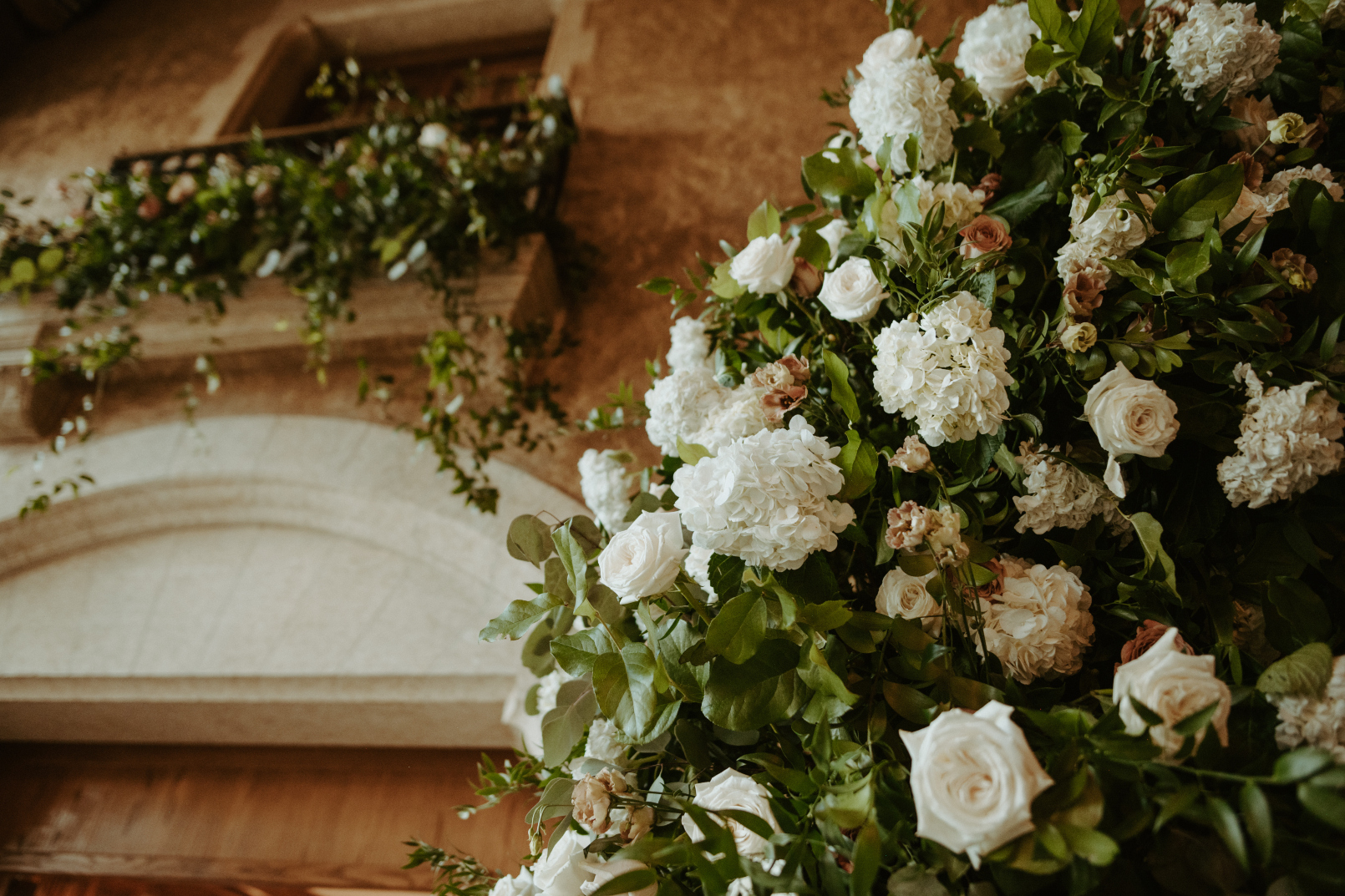 A close up of the gorgeous flowers from the arch with the balcony arrangement in the background.