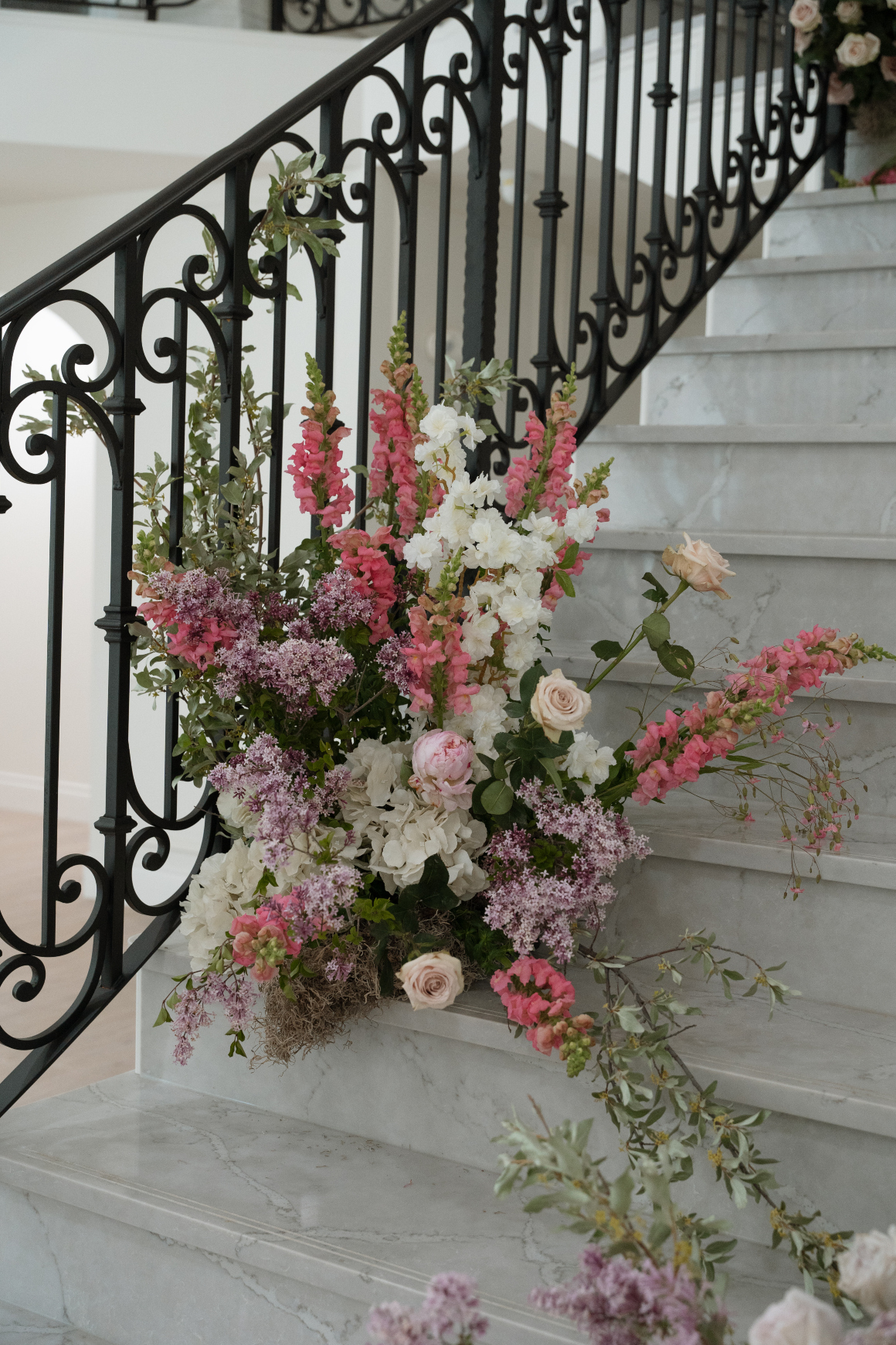 One of the arrangements leading up the grand staircase, earthy in style with snapdragons, cherry blossoms, hydrangea, peonies, roses, lilacs and moss.