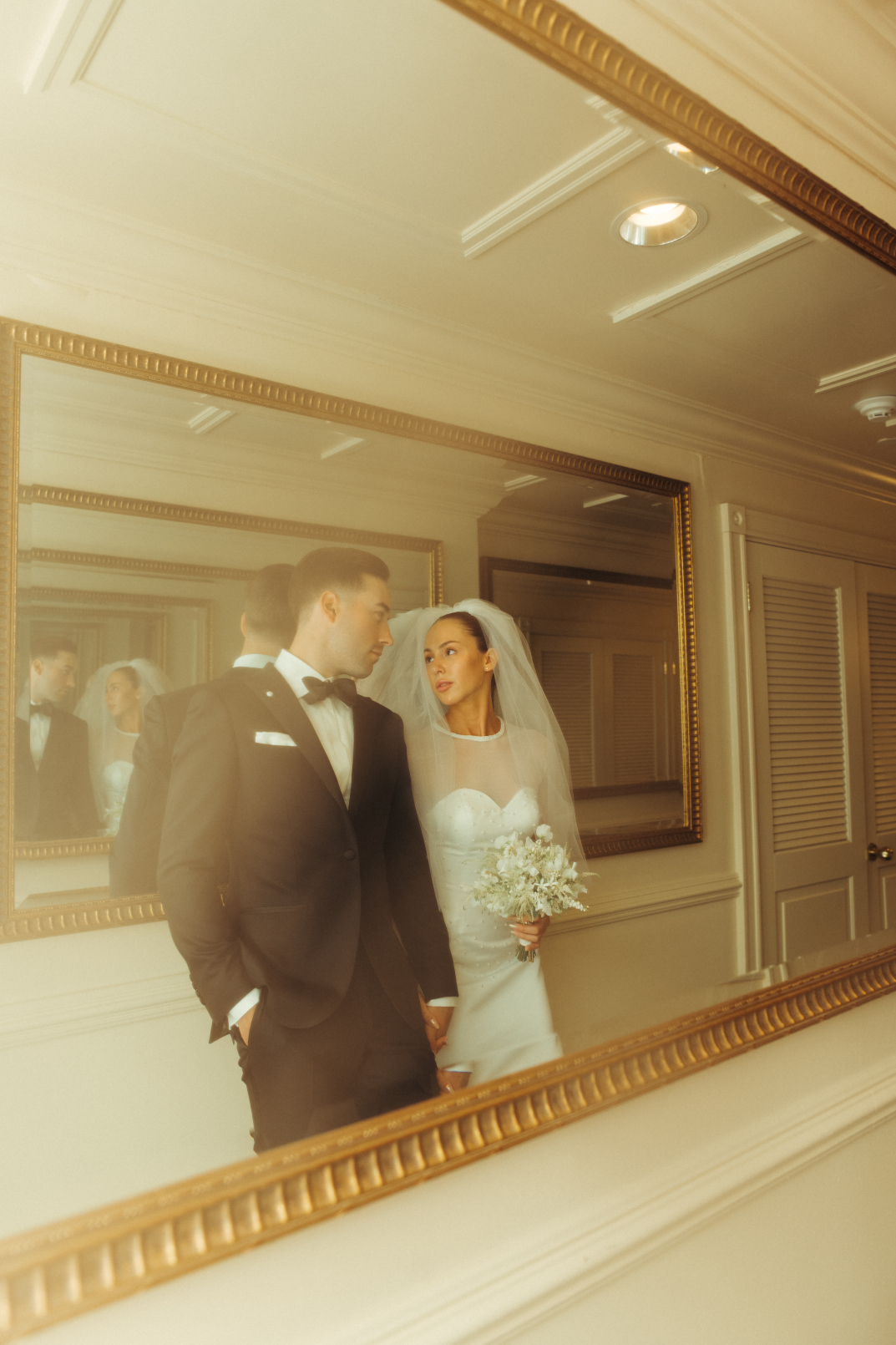 Tyller and Carter are in the hallway with the framed mirrors, leaning against one wall, and the picture shows both them as well as the repeat of their reflections in the mirror.