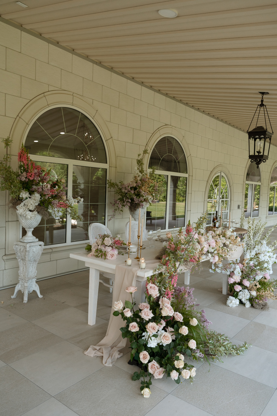 An alternative to the low and long arrangement, the sweetheart is adorned with several large arrangements in pedestal arrangements on pillars behind the table, and on the floor in front of the table.