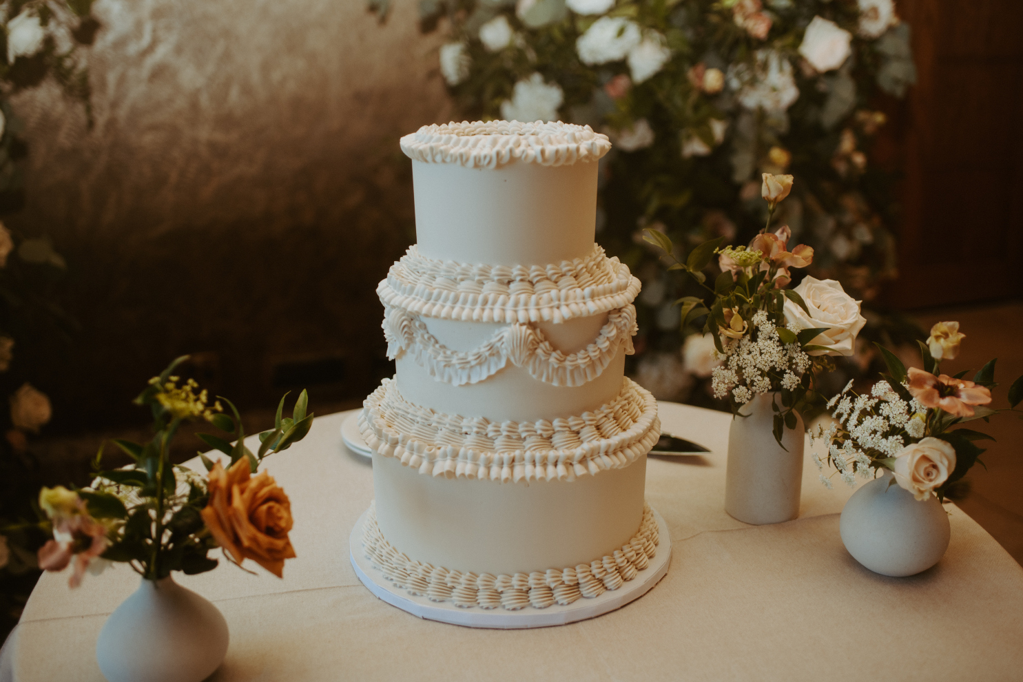 A close up of the classic ivory three-tiered cake adorned with fluffy icing ruffles.