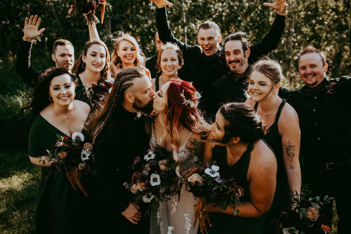 Haley and Greg share a kiss as their bridal party surround them, cheering.