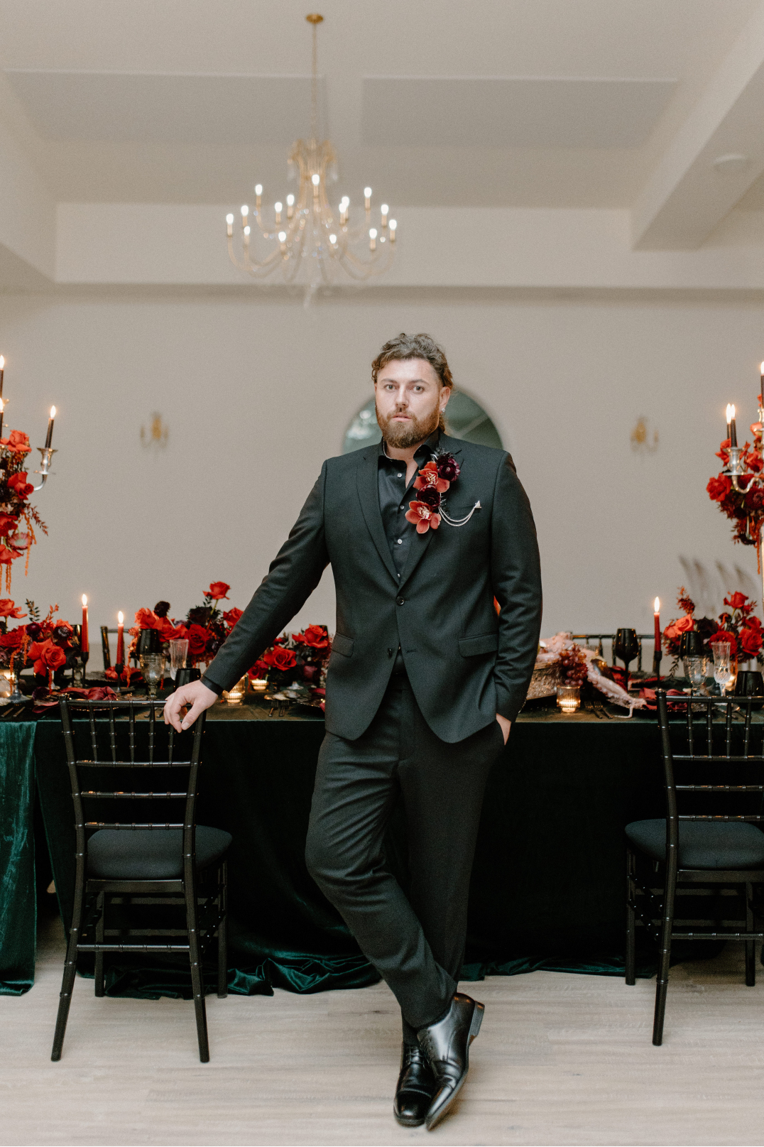 Dracula stands alone in front of the table, casually holding on to the corner of one of the black chiavari chairs.