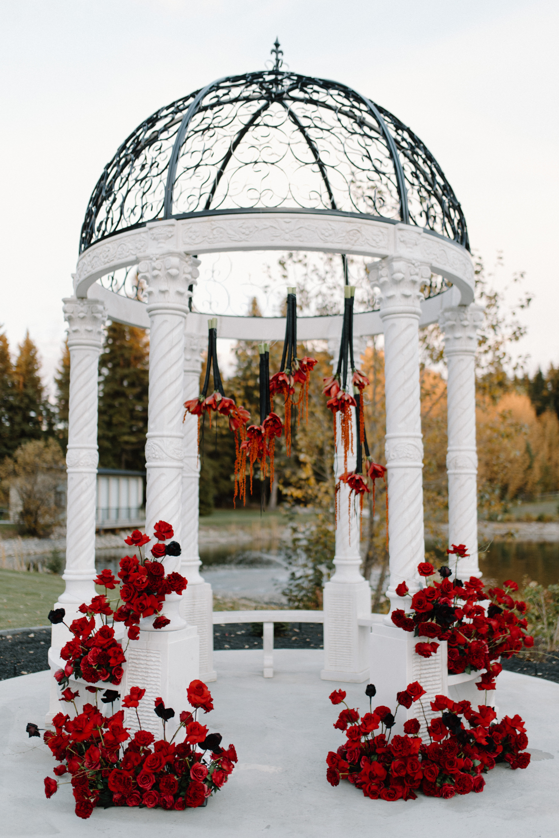 The sophisticated gazebo out on Archway Manor grounds, embellished with clusters of gorgeous red arrangements and stunning red blooms suspended by black satin ribbon.