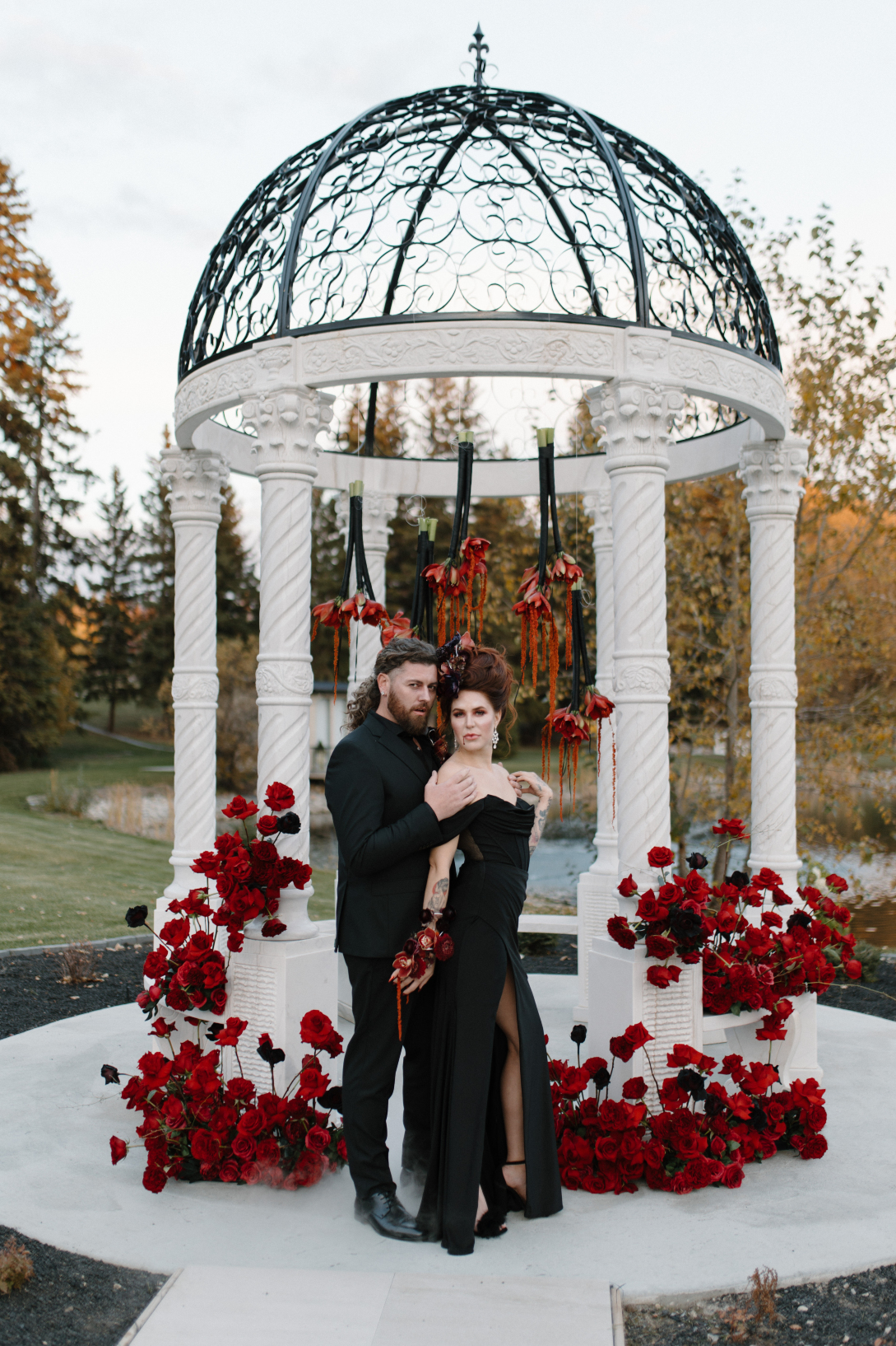 Dracula and his bride embrace in front of the amazing gazebo, surrounded by majestic red arrangements.