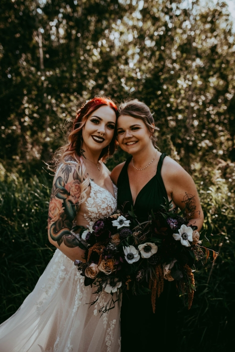 Haley and our very own, Erin, standing closely, holding their bouquets and smiling.