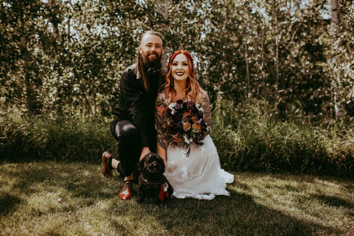 Haley holds her bouquet as her and Greg kneel down next to their doggo, smiling at the camera.