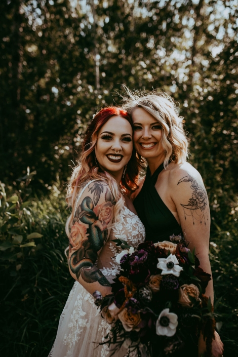 Haley and her maid of honour standing closely, smiling holding their bouquets.