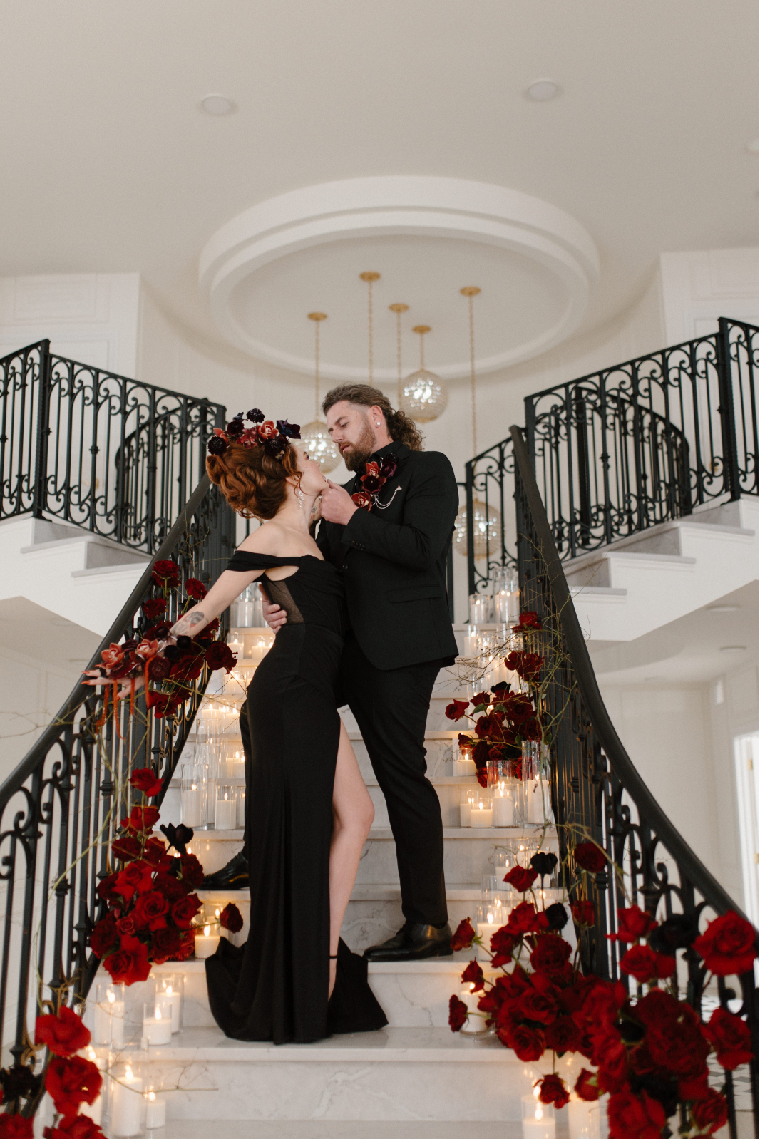 On the staircase, Dracula's bride holds on to the railing behind her with one hand, staring up at Dracula, who is holding her chin in one hand as though he may lean in for a kiss.