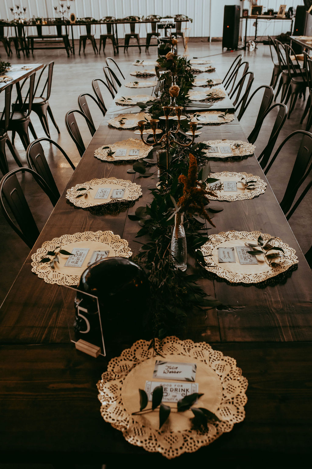 Close up of the table deisgn with cute paper doily settings, with an individual piece of italian ruscus, acrylic table numbers, candelabras, table garland and bud vases.