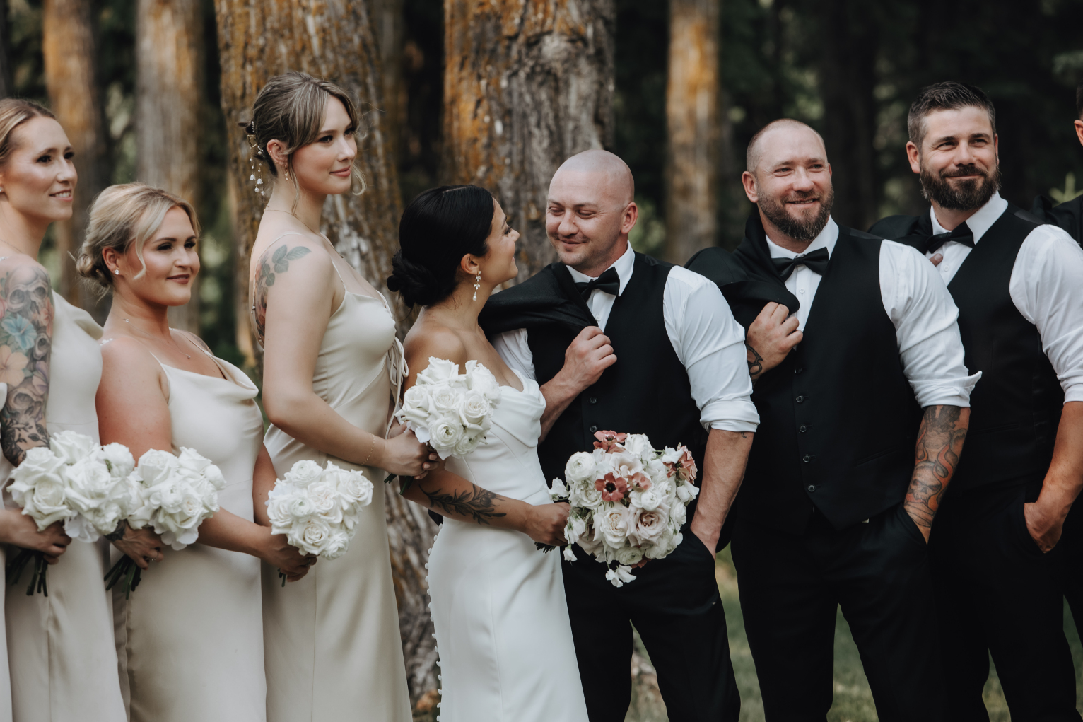 Kristen and Chris gazing at each other with their wedding party by their sides, posing for the picture.