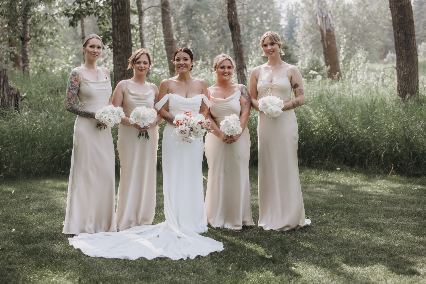 Kristen and all of her beautiful bridesmaids in their champagne gowns, standing together and smiling.