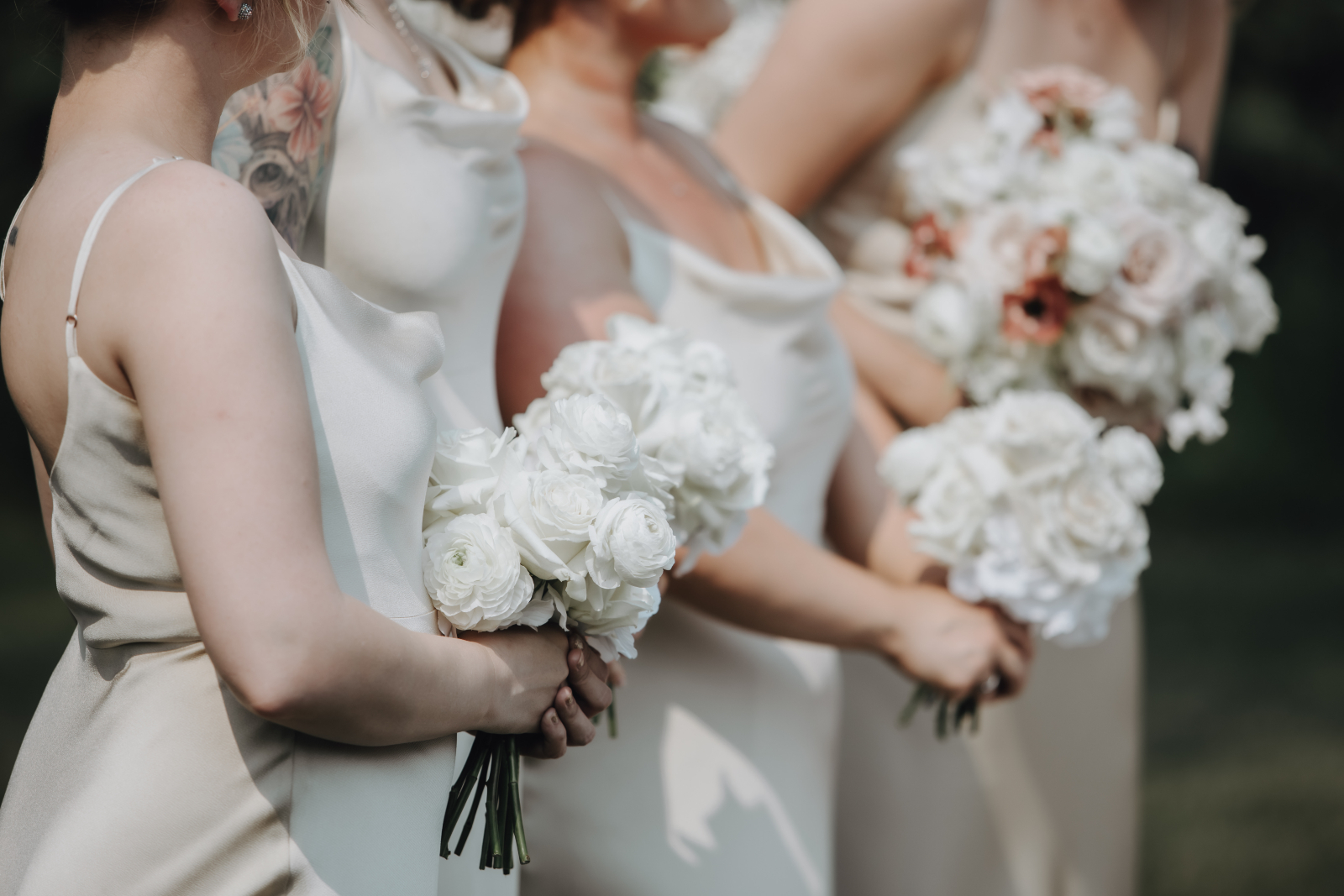 The bridesmaids lined up at the ceremony wearing gorgeous champagne satin gowns, carrying all white bouquets.