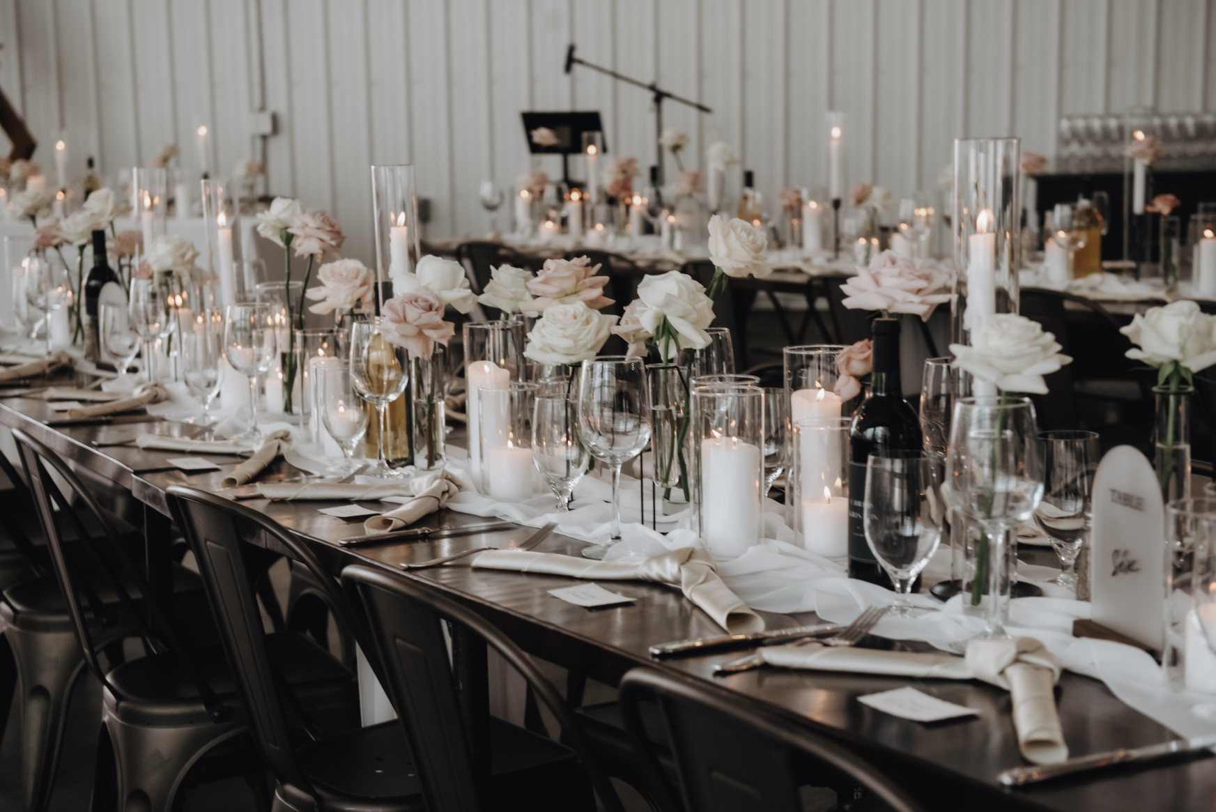 Guest tables featured a soft white table runner, filled with clusters of pillar candles and tapered candles, along with budvases filled with roses.