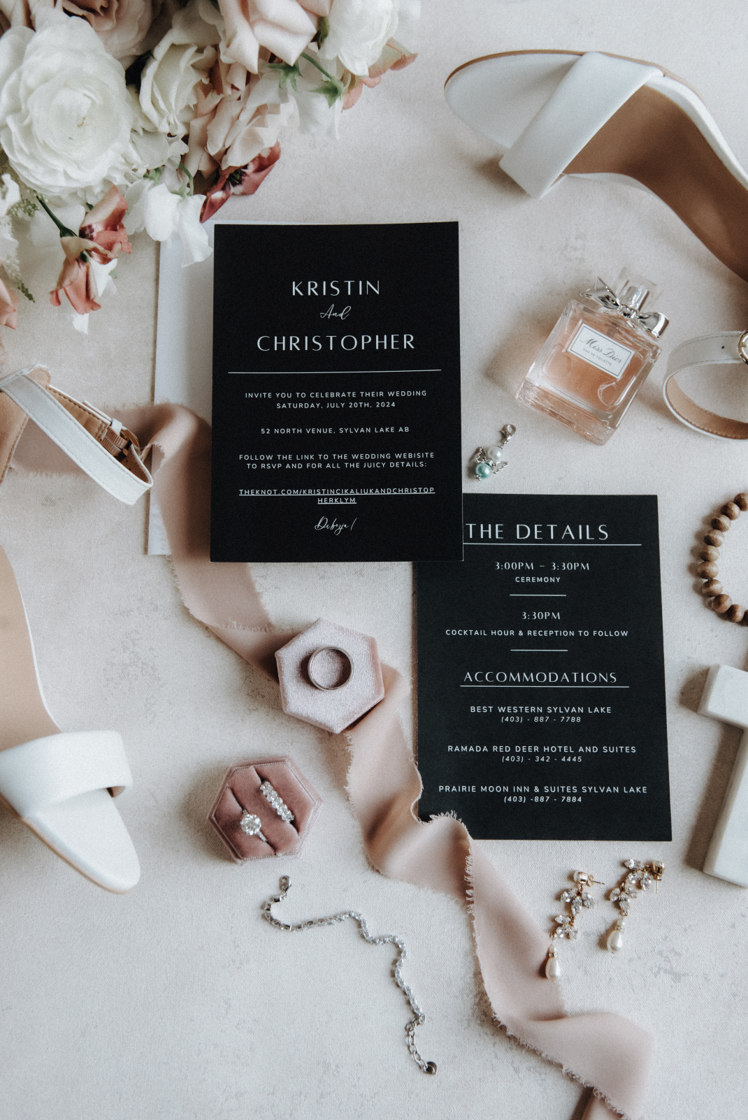 A gorgeous flatlay of the some of the bridal details including the invitation, her shoes, perfume, the rings along with some silk ribbon and part of the flowers from the bouquet visible at the top corner.