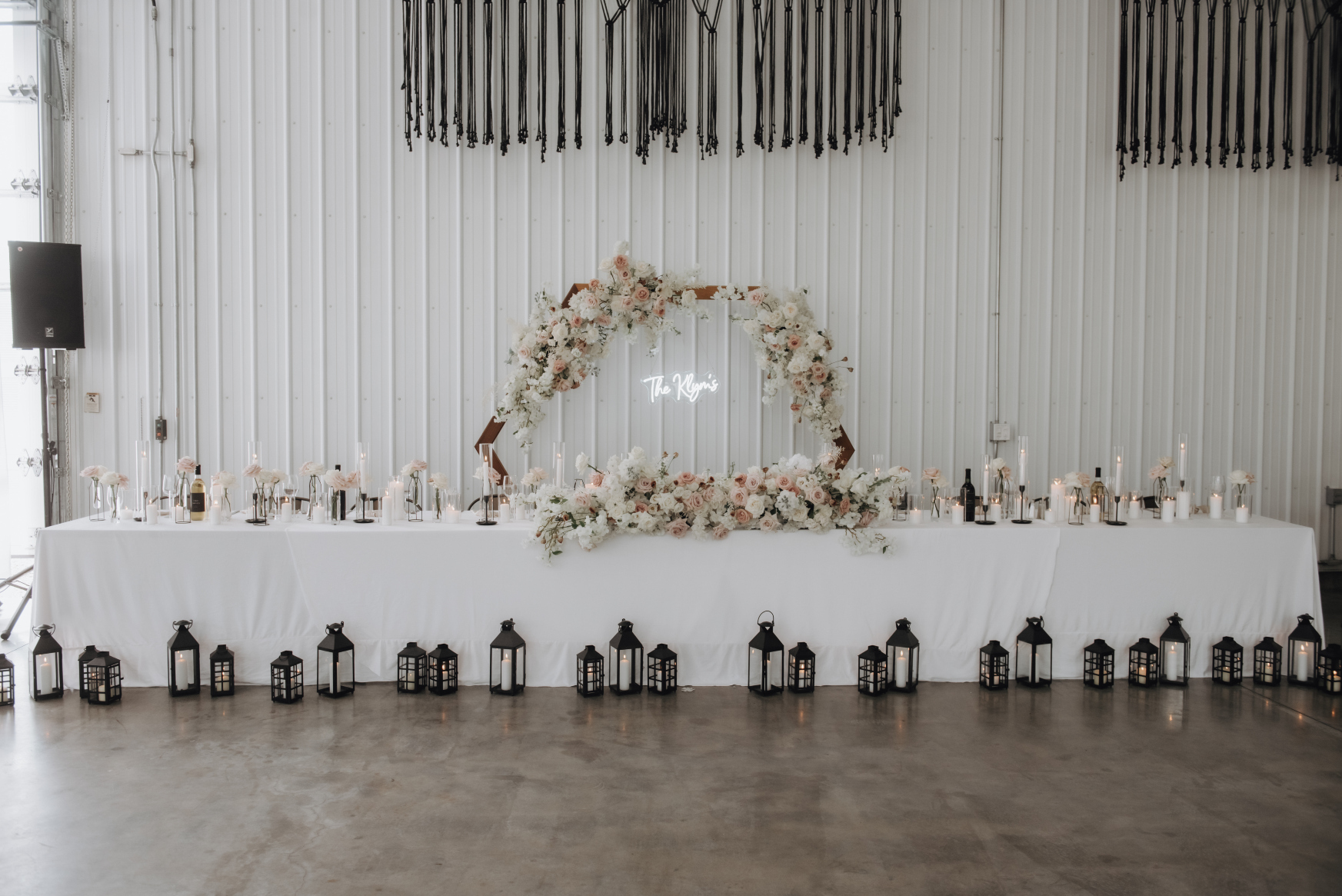 The head table for the wedding party had the hexagon arch behind it, with a neon sign reading "the Klym's". Only the top part of the arch shows flowers, the rest were removed and used as an arrangement at the front of the head table. Gorgeous black lanterns at various heights were displayed on the floor in front of the head table.