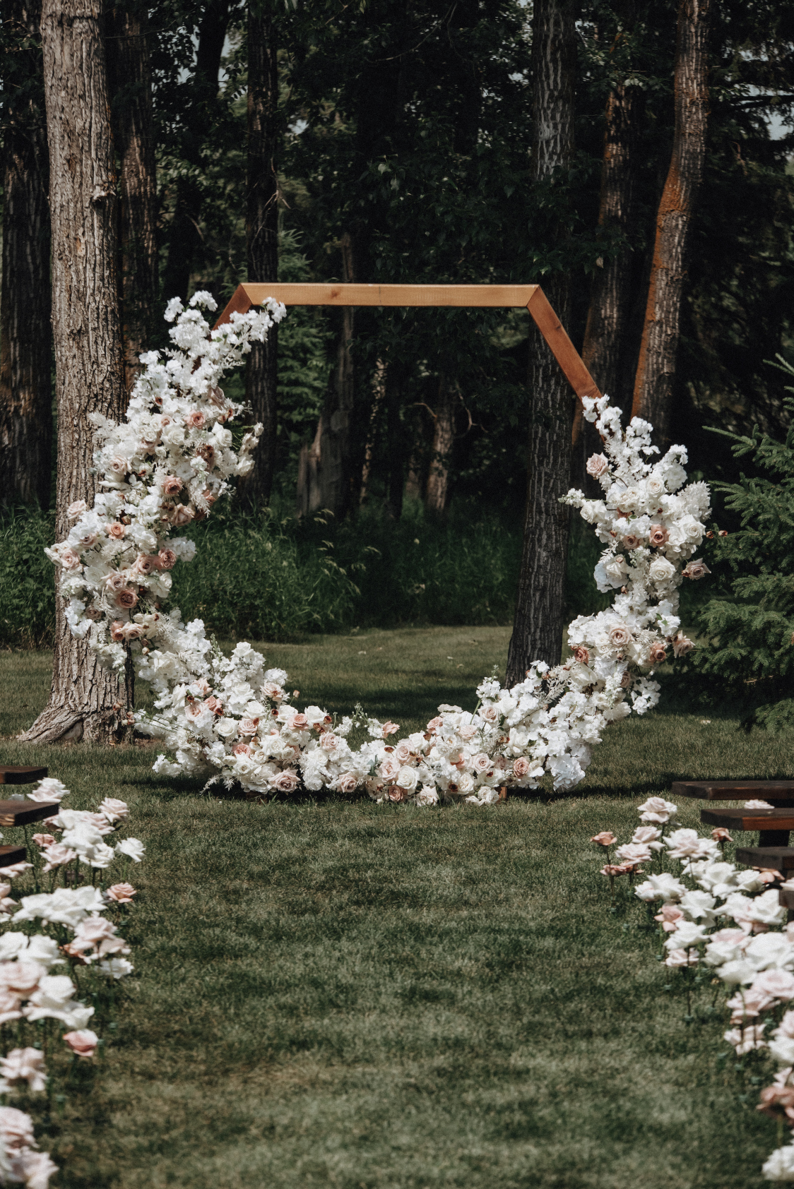 The wooden, hexagonal archway, with the flowers making a 'U' shape, covering the bottom portion in a stunning mixture of white and blush flowers.