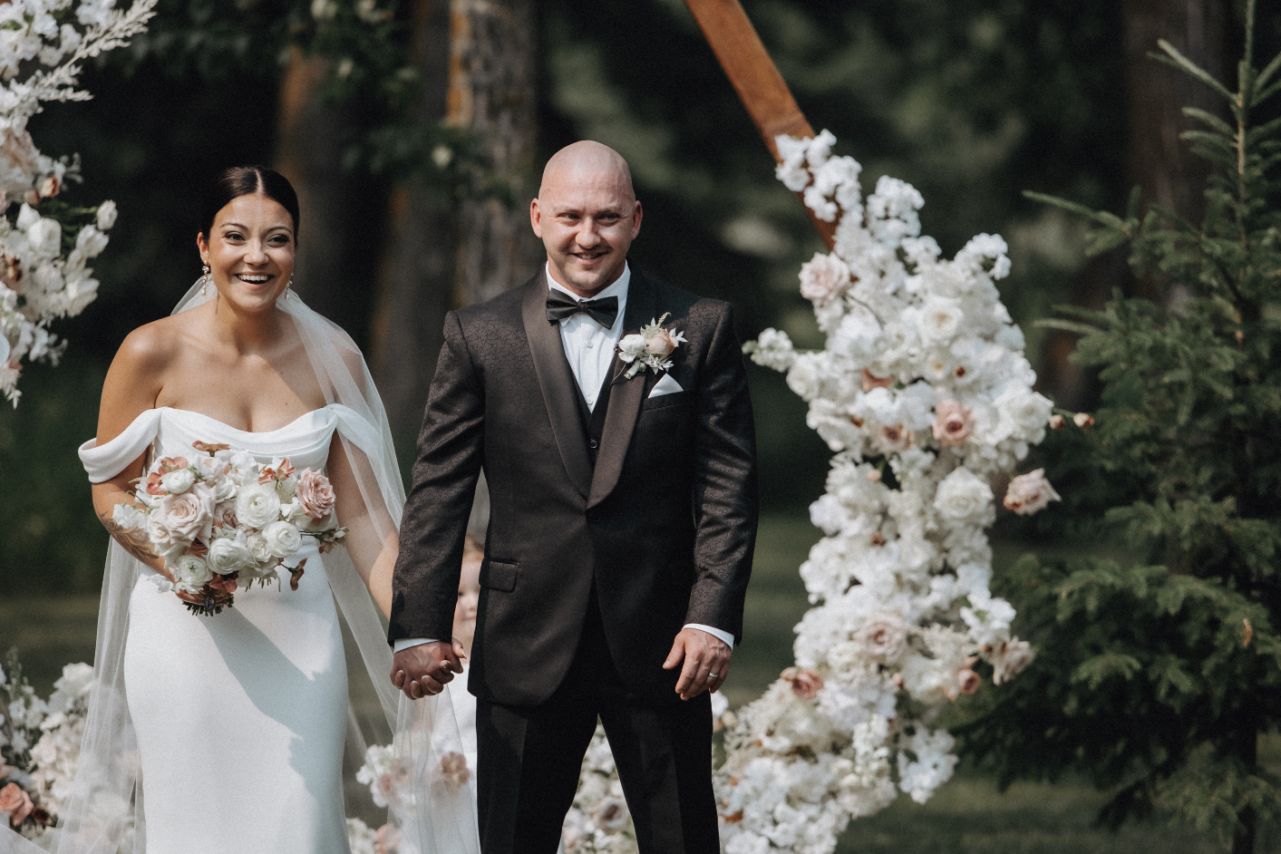 Mr. and Mrs. Klym at the end of the ceremony, with huge smiles in front of their archway.