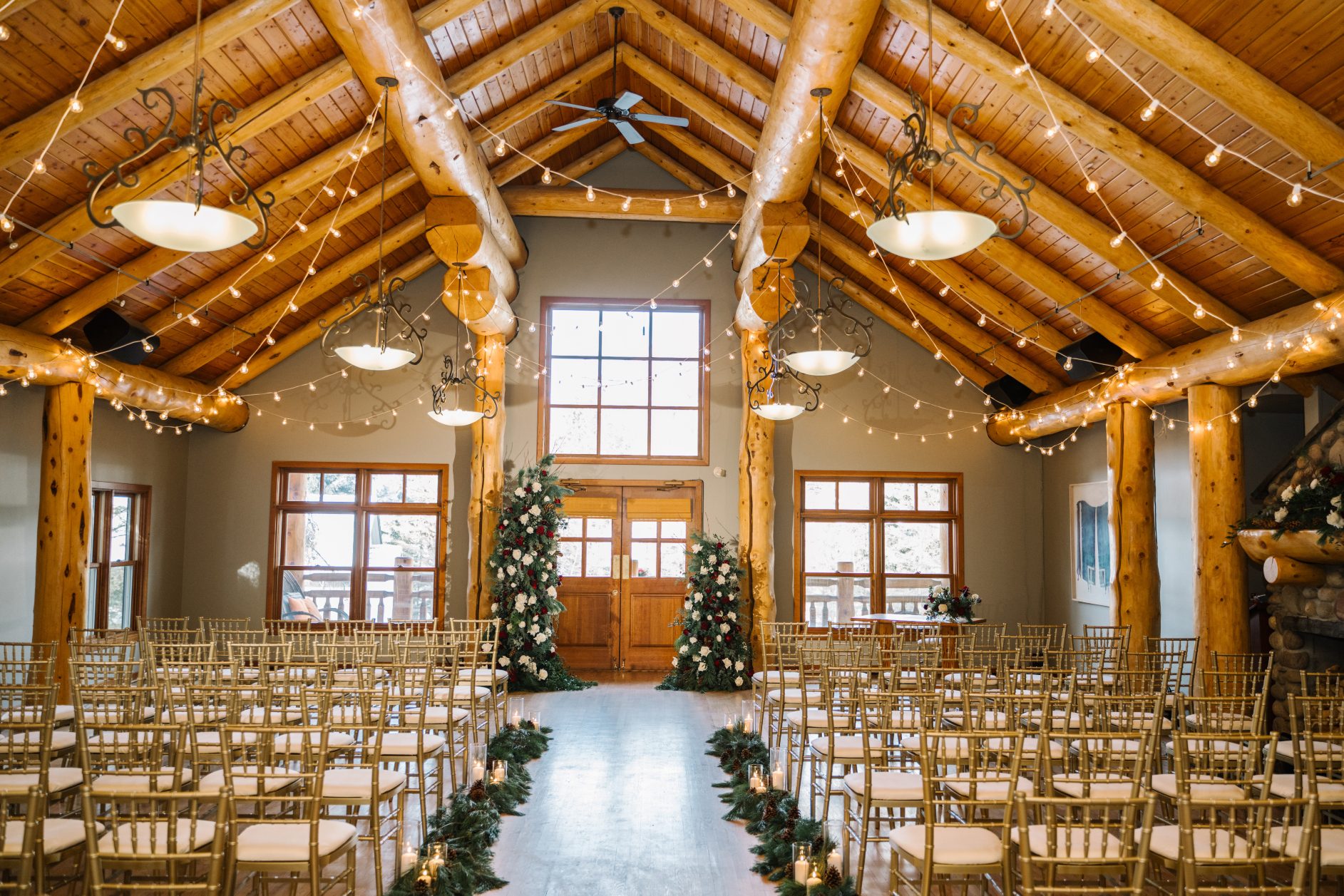 Arch Piece The ceremony set up was beautiful with gold chiavari chairs, pine boughs and pillar candles lining the aisle and an impressive asymmetrical arch piece overflowing with flowers and greens.