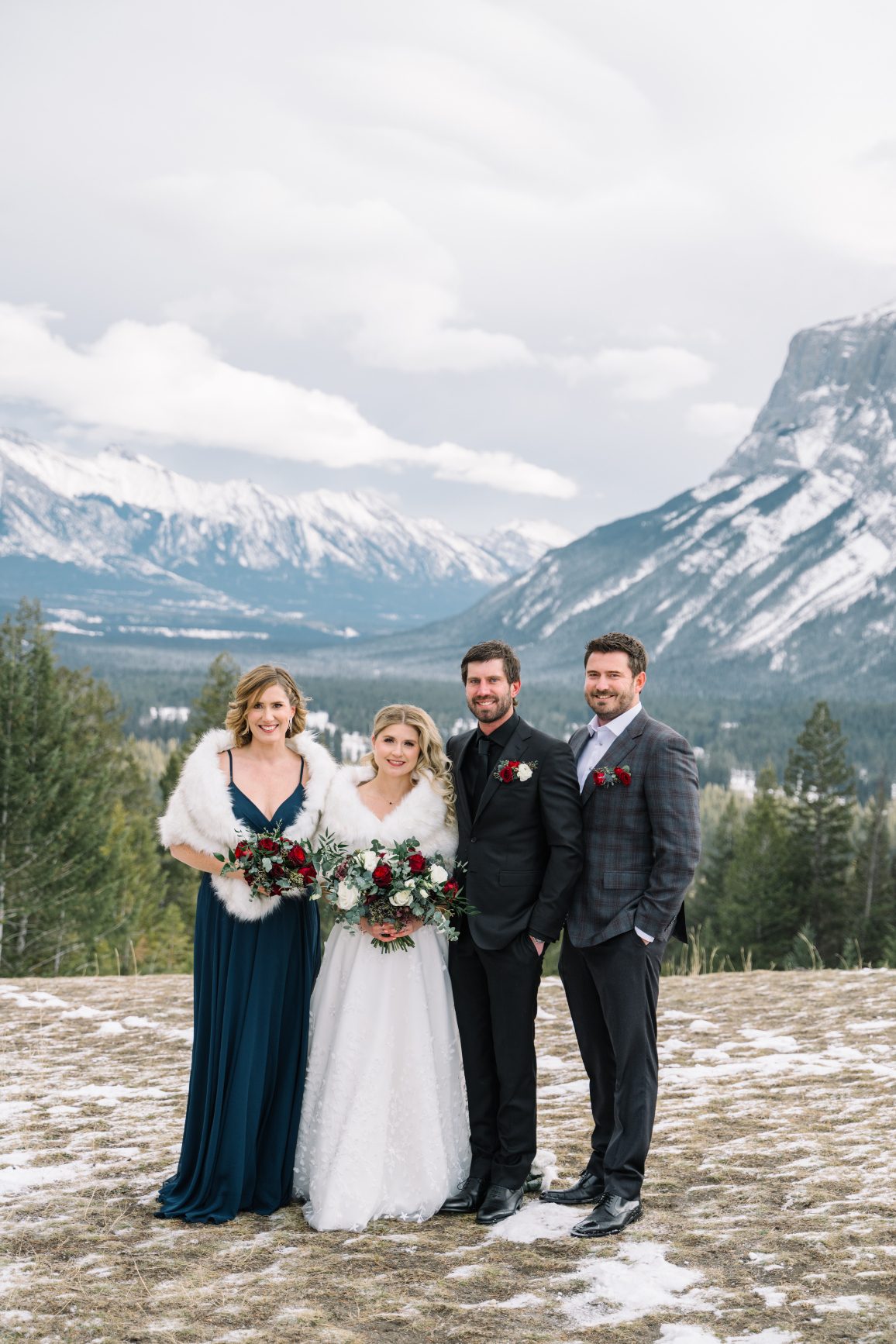 Calgary Wedding and Portrait Photographer Courtney and Adam stand with his siblings, with picturesque mountain views behind them, smiling at the camera.