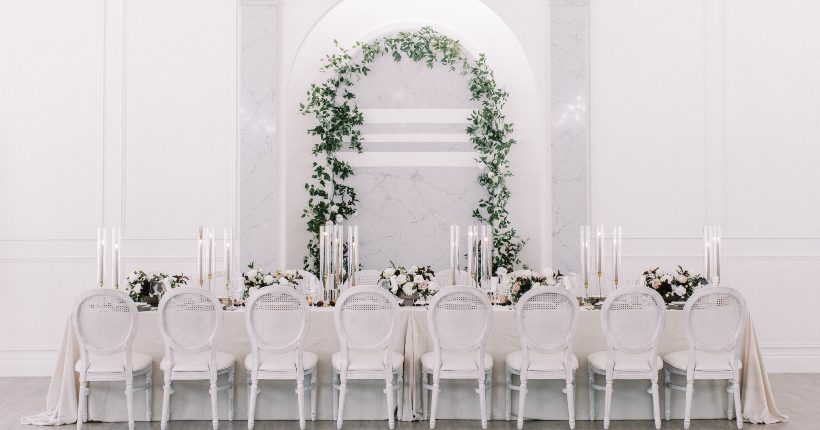 Feature Thin Tablescape design at Archway Manor, featuring an arch of reenery behind the table, taper candles, and stunning Calyx centrepieces.