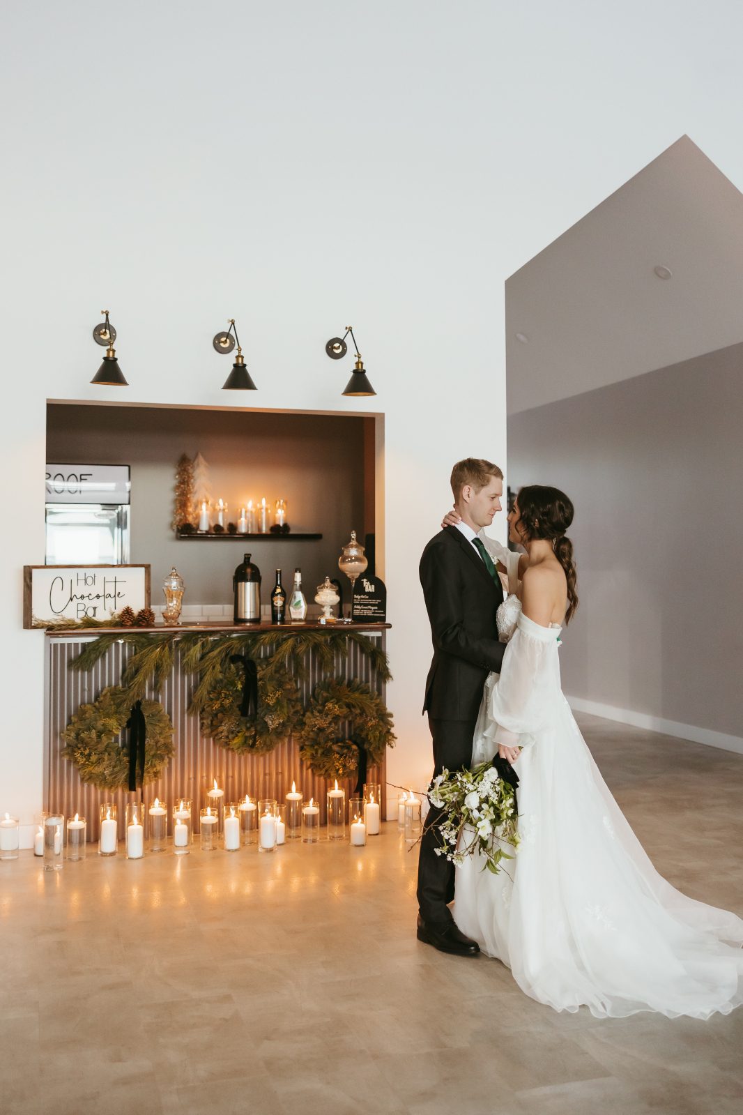 The couple embracing in front of the hot chocolate bar, which also has been lit up with oodles of lit candles.