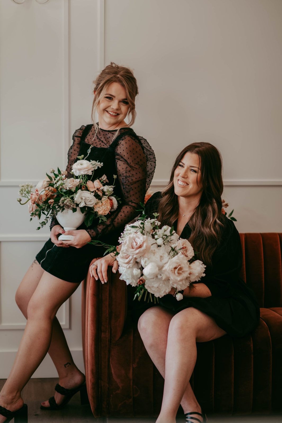 Calyx's Erin and Travis sitting together on a couch. Erin holding an arrangement and Travis a coordinating bridal bouquet.