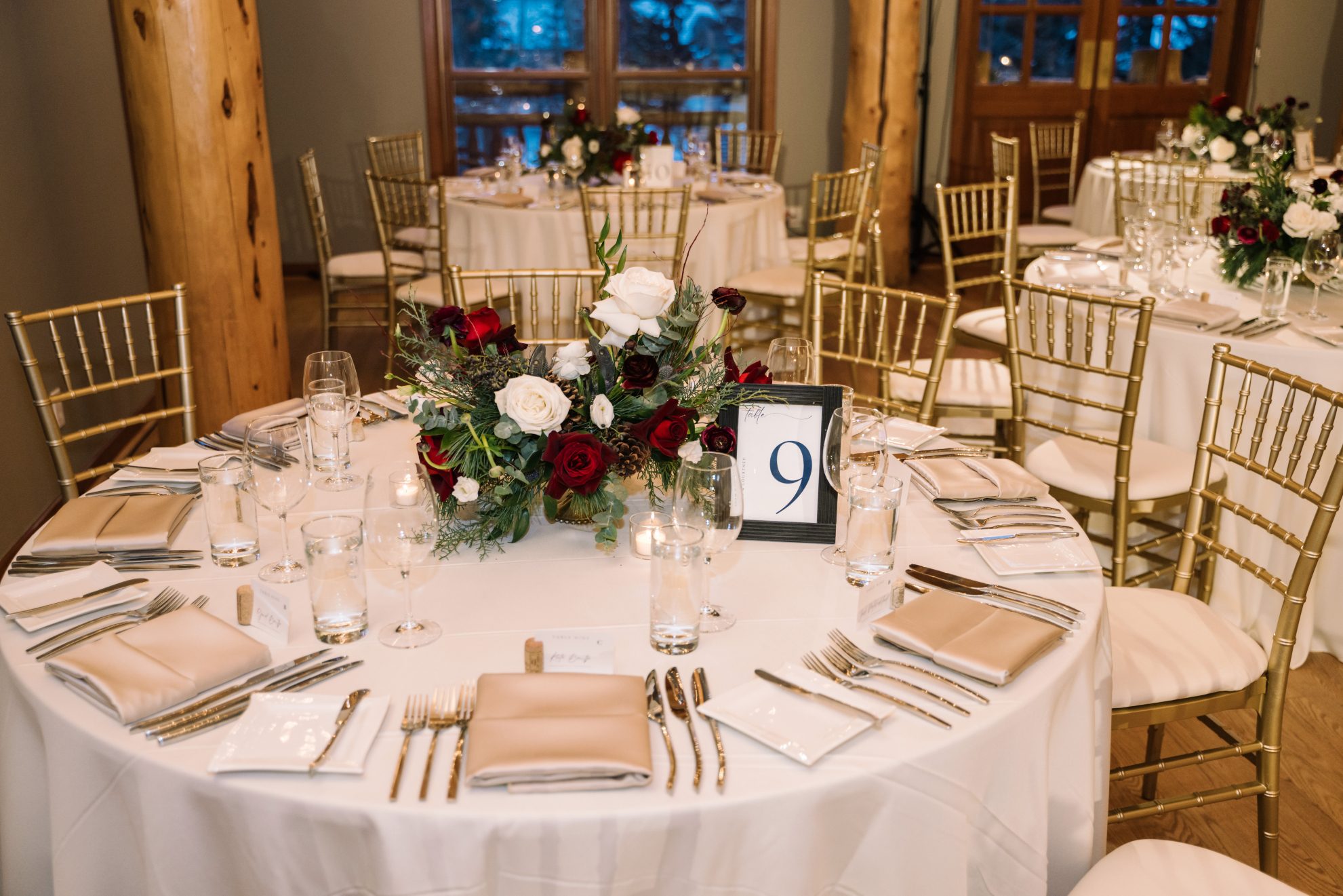 Calgary Wedding and Portrait Photographer Guest table with fabulous centrepieces in red and ivory, with a horseshoe nestled in for a personal touch.