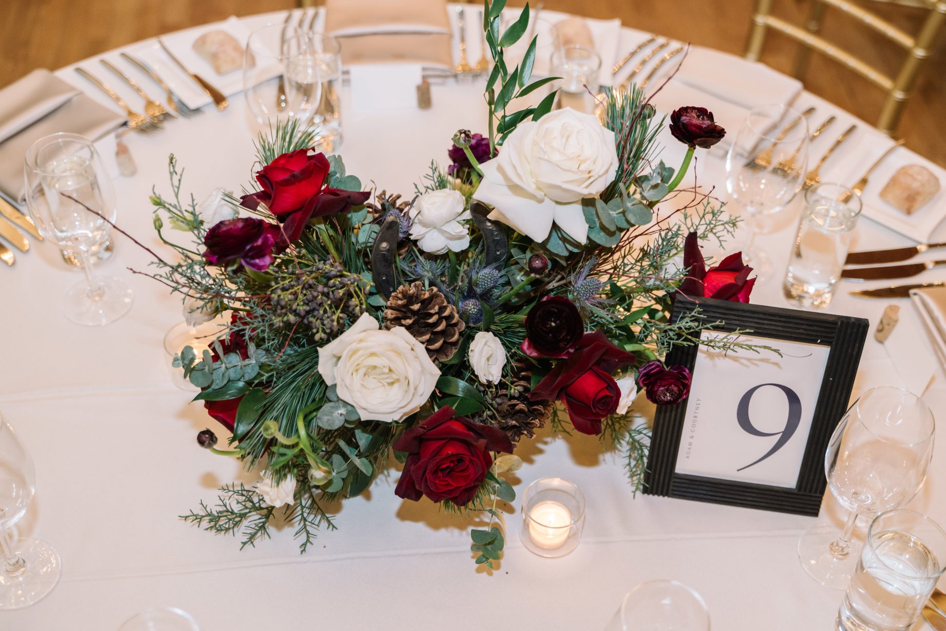 Calgary Wedding and Portrait Photographer A centrepiece from above, showing the stunning roses, ranunculus, eryngium, privet berries and hellebores with lush greens and pine cone accents.
