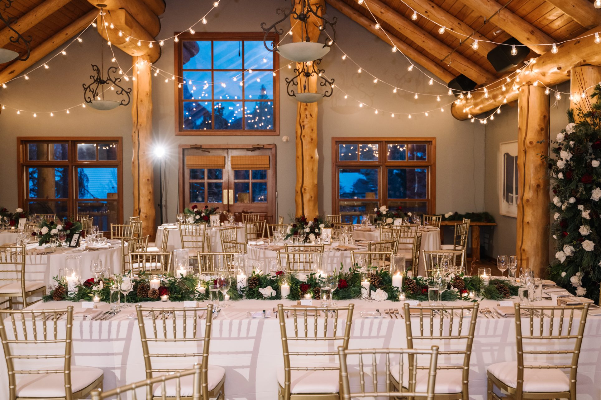 Head Table Centrepiece The head table set up elegantly with guest tables showing behind it, and strung lights across the ceiling above them.
