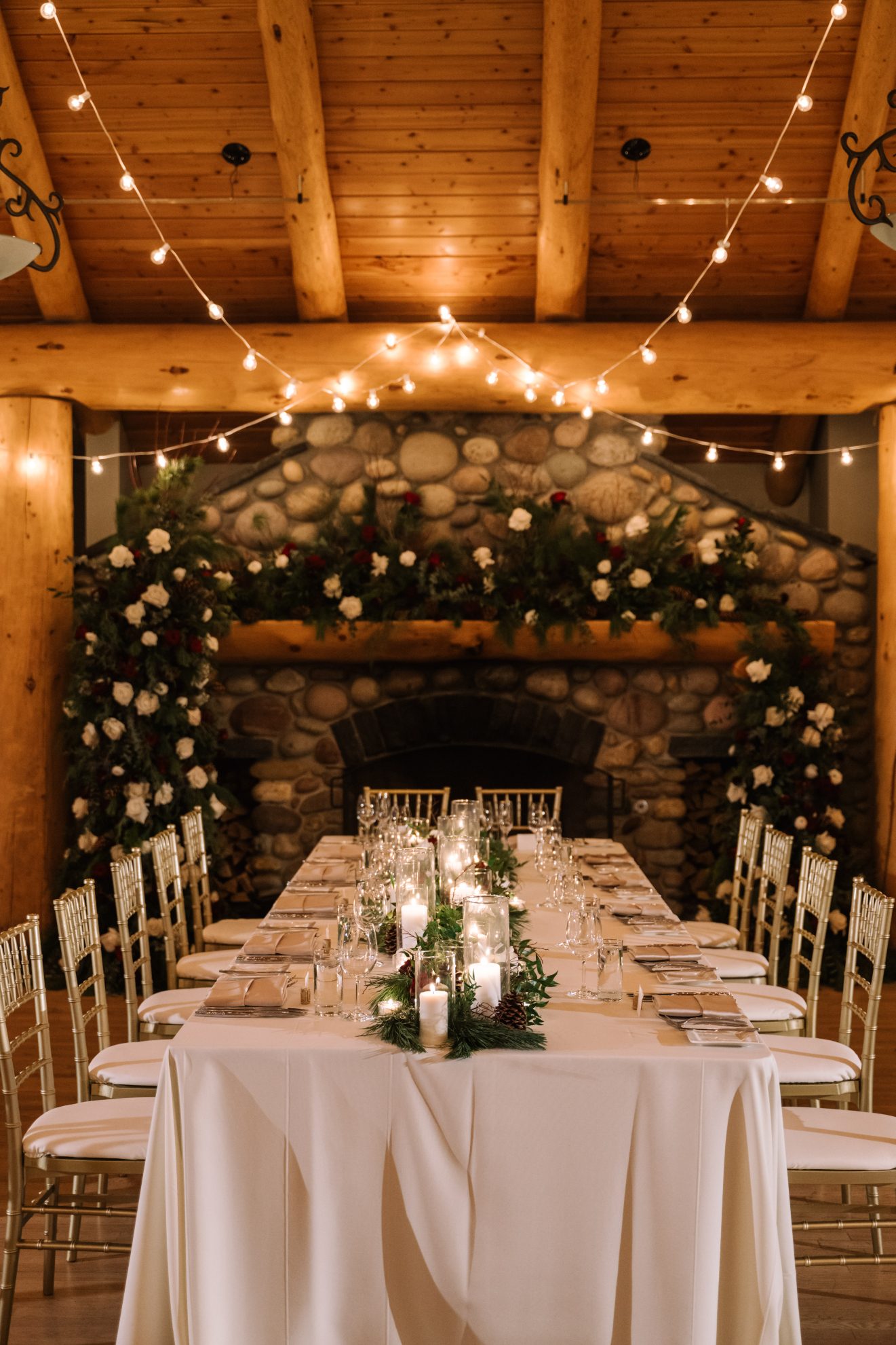 Calgary Wedding and Portrait Photographer The head table set up in front of the grand stone fireplace, both adorned beautifully with flowers.