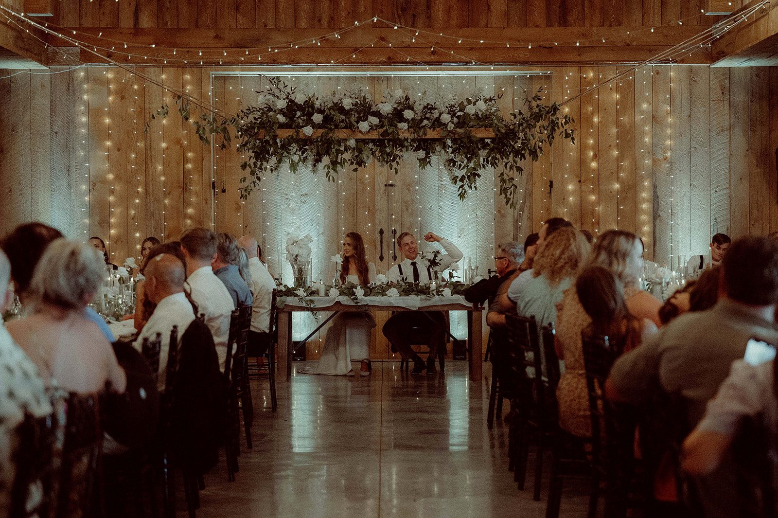 The beautiful couple sits at the head table with the impressive floral instalment suspended above them.