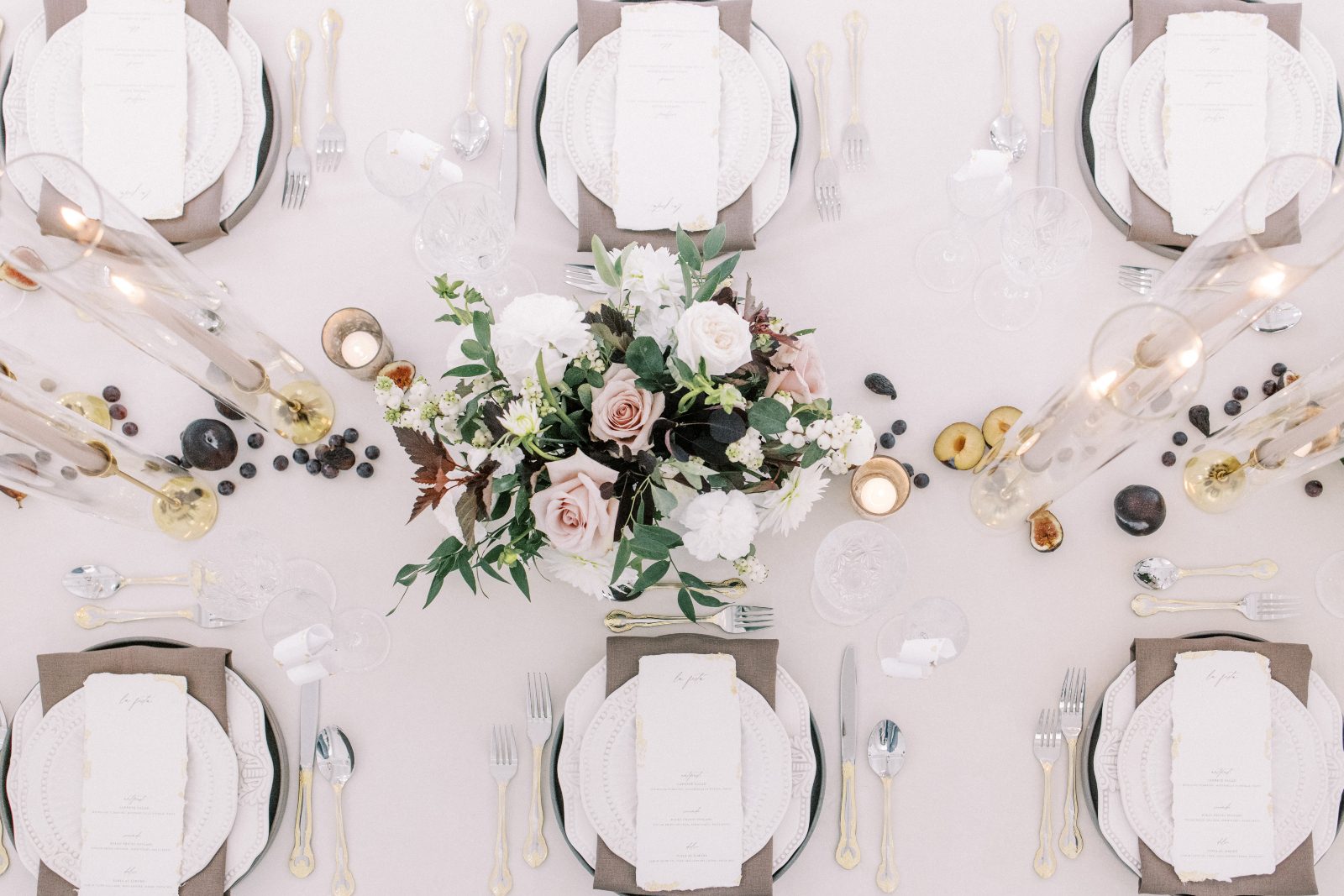 The tablescape from above, showcasing a stunning floral centrepiece, tapered candles, votive candles and perfectly styled place settings.