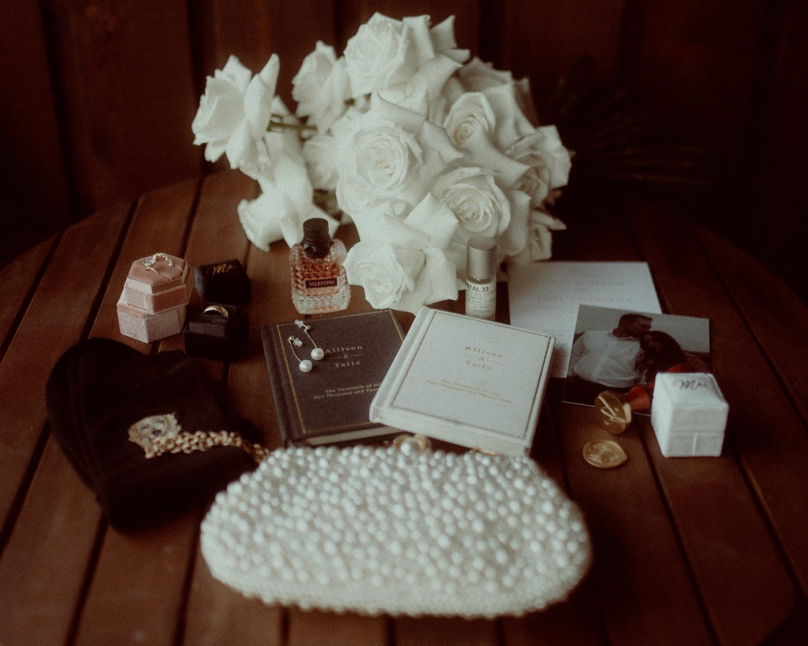 Stunning image of Allison's bouquet and accessories - rings, vow books, clutch and perfume.