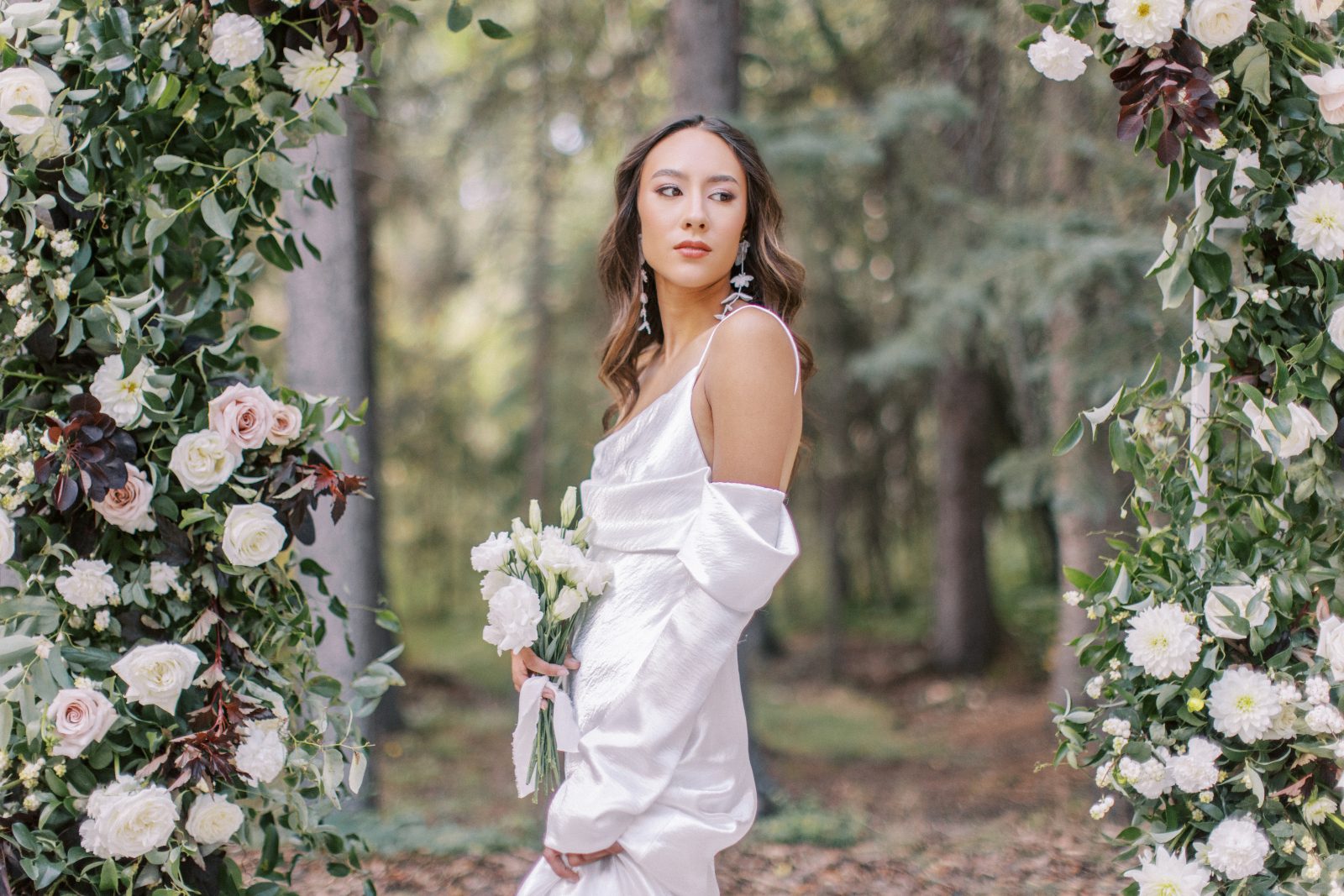 A close up of the trendy satin gown as the model holds a small simple posy bouquet.