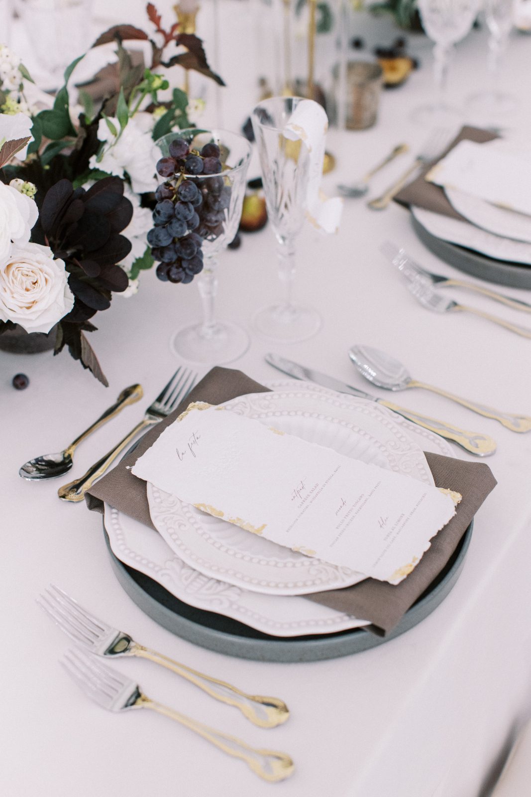 Chic place settings with thoughtful layering of places, luxe silverware and crystal glassware.