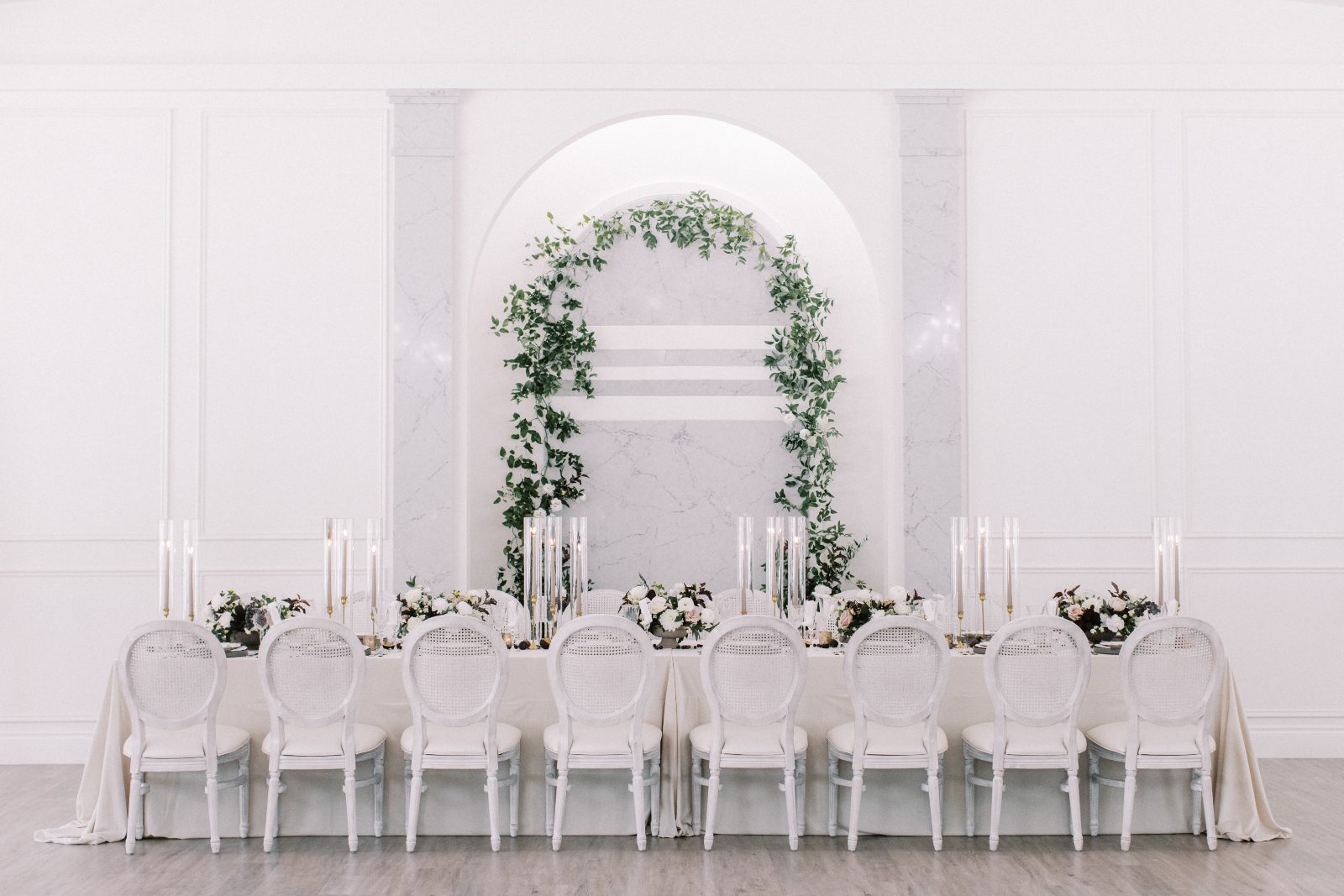 Showcasing the gorgeous architecture of the venue with an arch accented with greenery behind the tablescape.