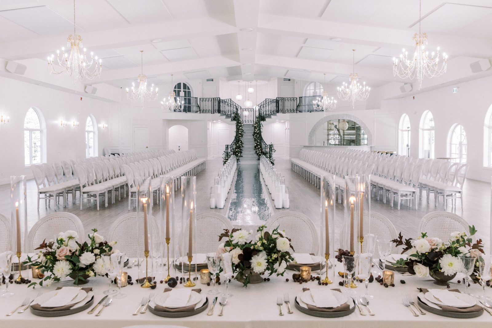 From behind the tablescape, showcasing the stunning table set up with the dramatic grand staircase and runway set up in the background.