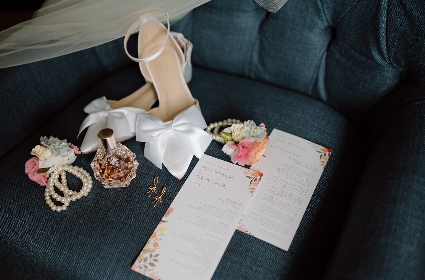 Mya's shoes, perfume, earrings and wedding invitation along with a couple of wrist corsages displayed on a beautiful teal couch.