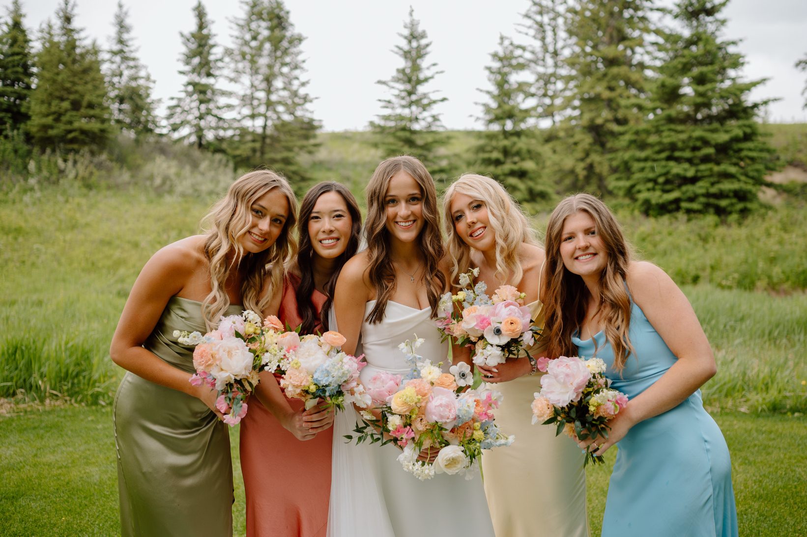 Mya with her beautiful bridesmaids huddled in closely together smiling radiantly.