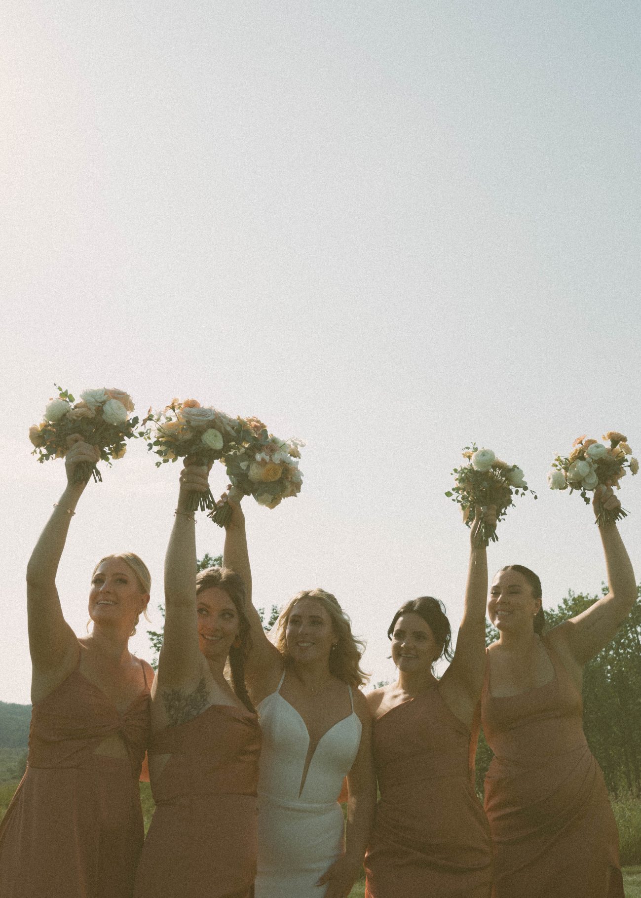 Katrina and her girls with big smiles, holding their bouquets up high cheering.