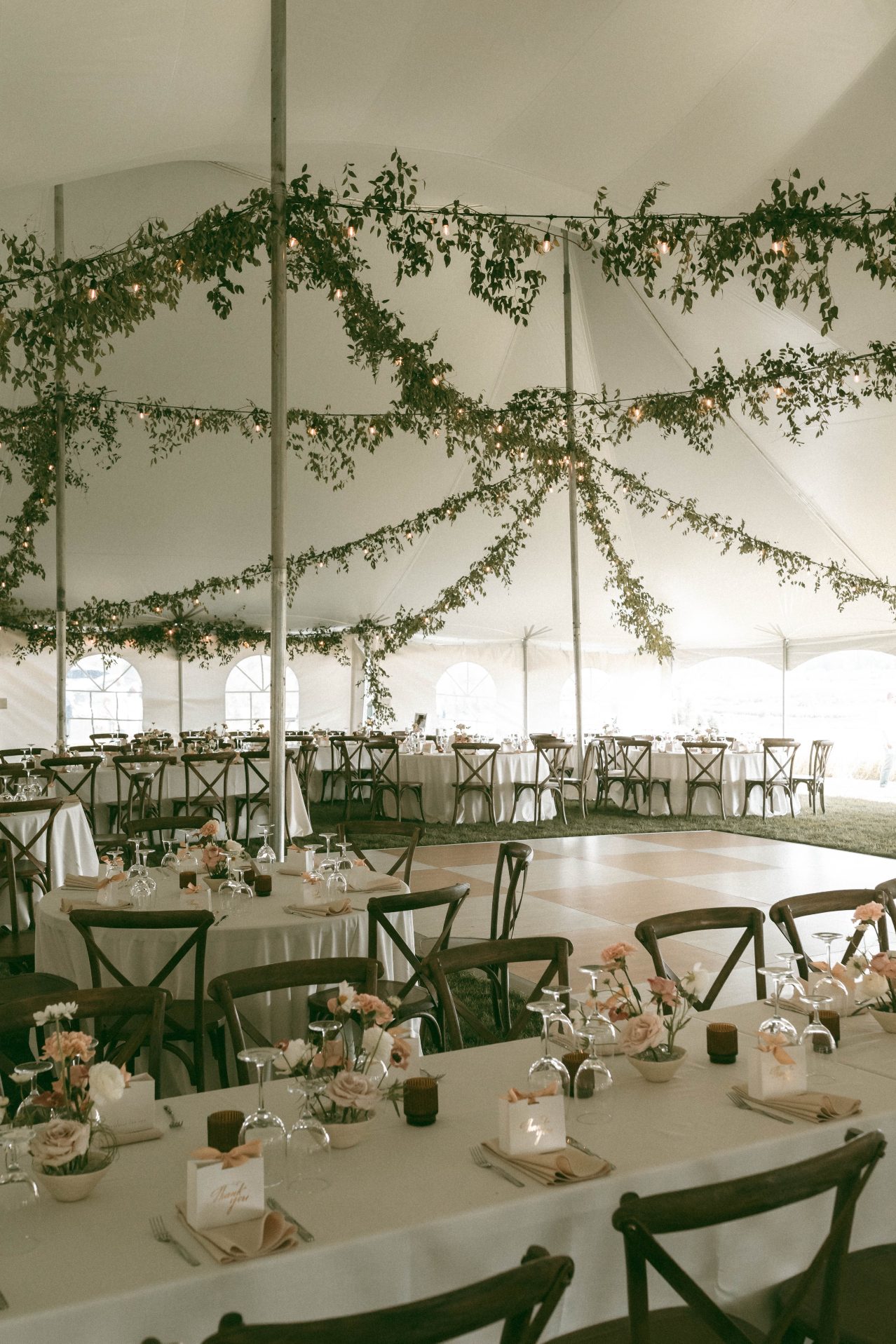 Absolutely magical tent reception with lights and garland draping across the ceiling, thoughtfully planned out decor and the summer sun streaming in through the open sides.