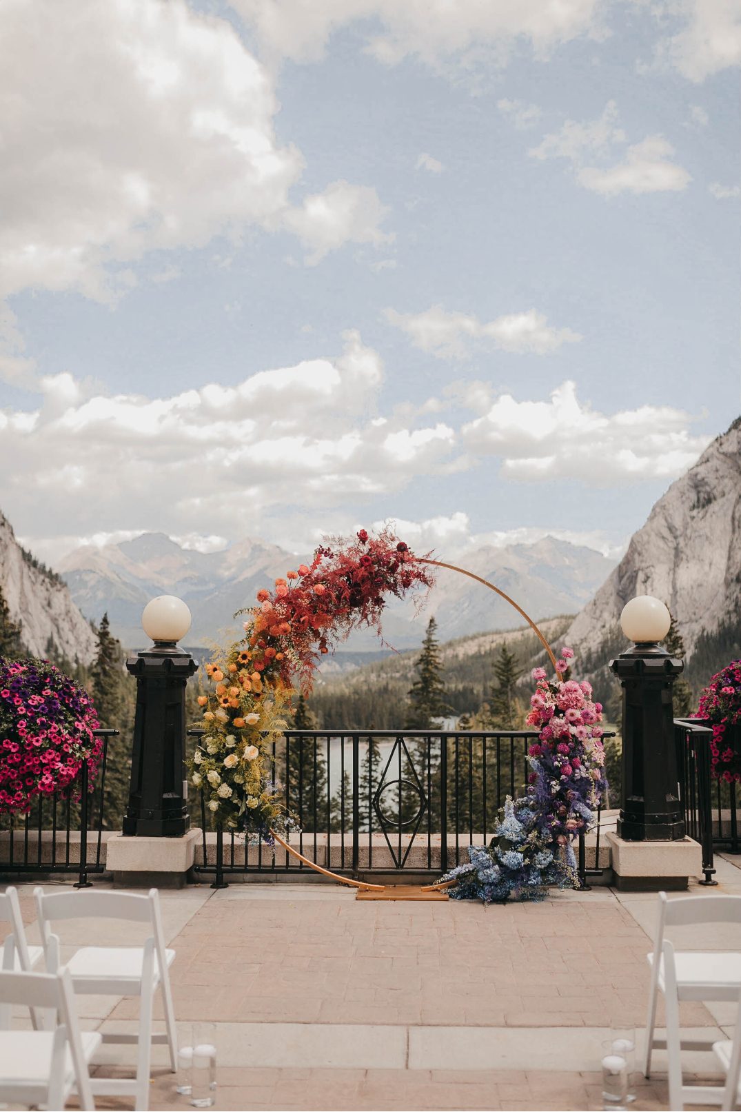 Symmetrical photo of the rainbow ceremony arch set between two mountain peaks.
