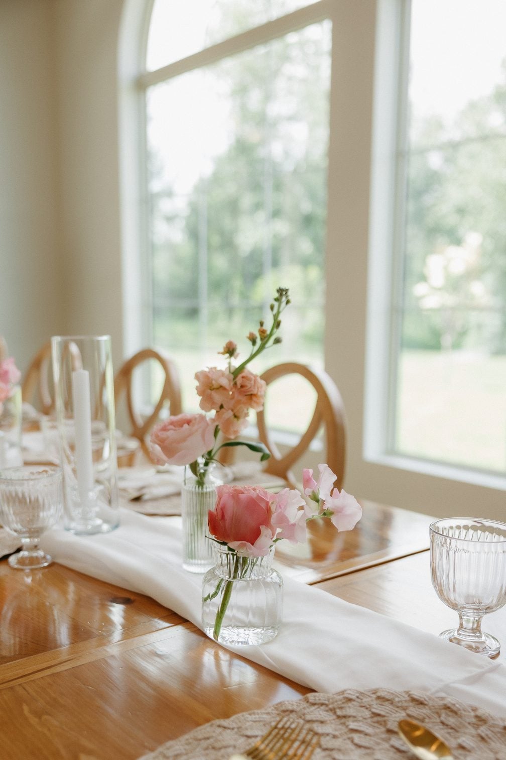 Another guest table bathed in natural light, with peonies, roses, stock and sweet peas in bud vases.