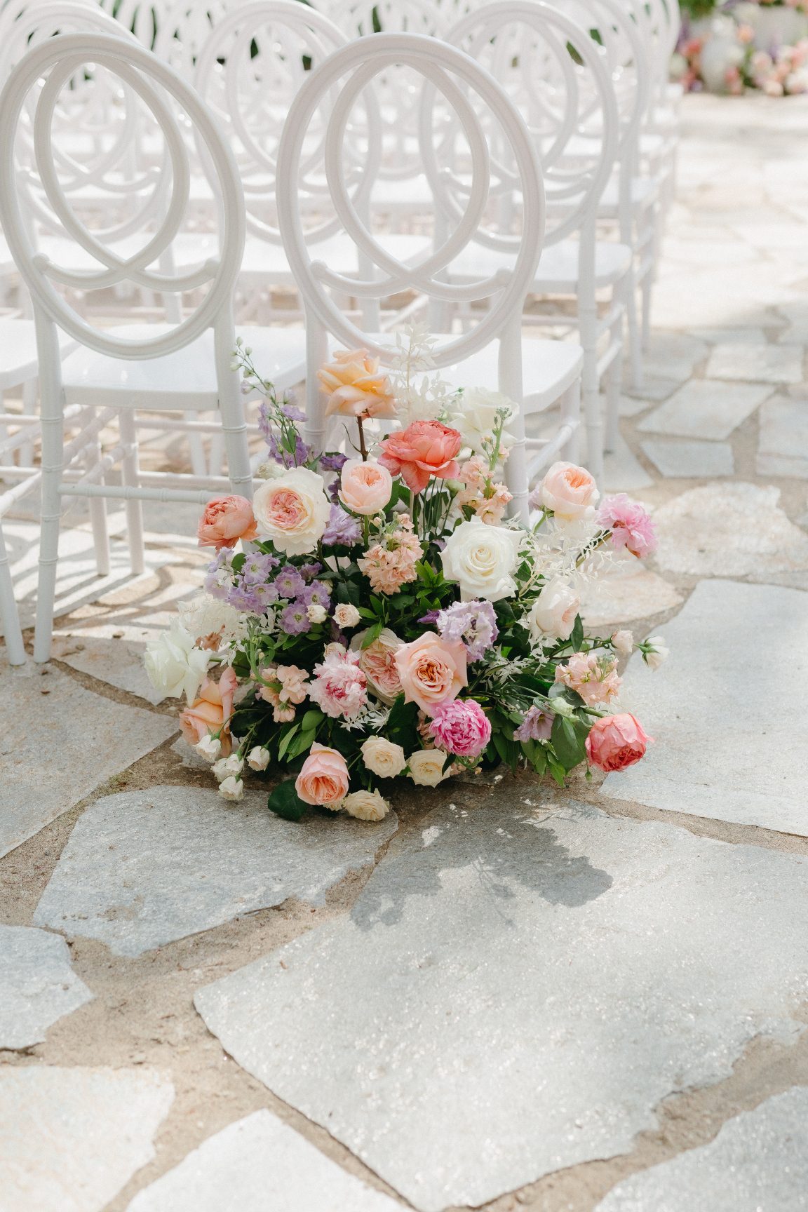 A beautiful pastel arrangement of peach, blush, ivory and lavender marking the entrance of the aisle.