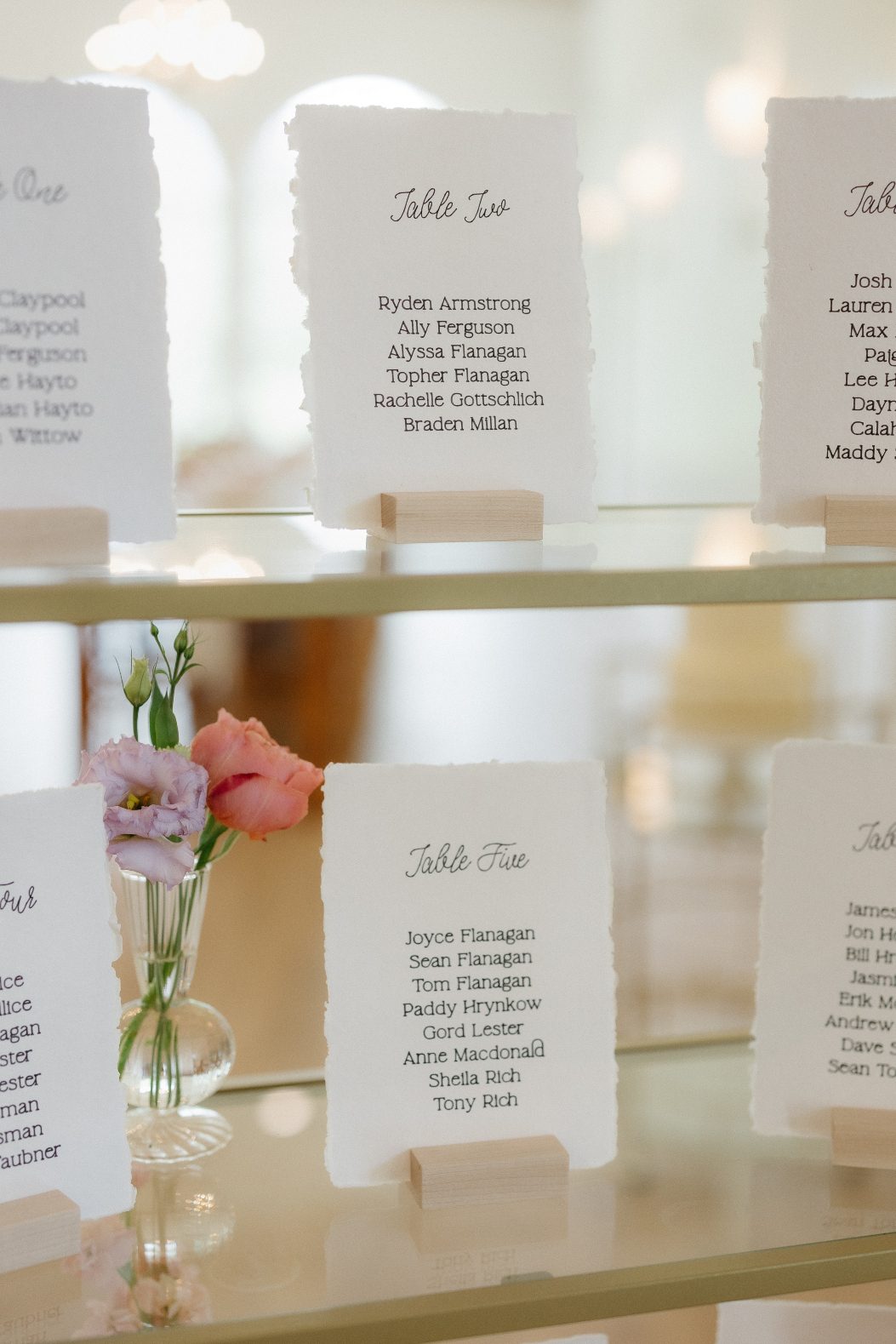 Close up of the bud vase with pink and lavender blooms on the shelf of the seating chart.