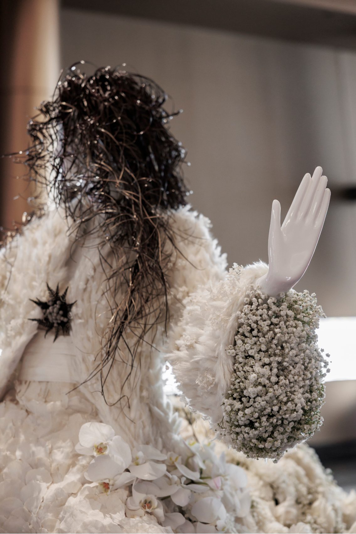 Close up of the mannequin's hand wrapped in baby's breath inside the cuff and textured floral jacket detail for the Shania Twain Fleur de Villes display.